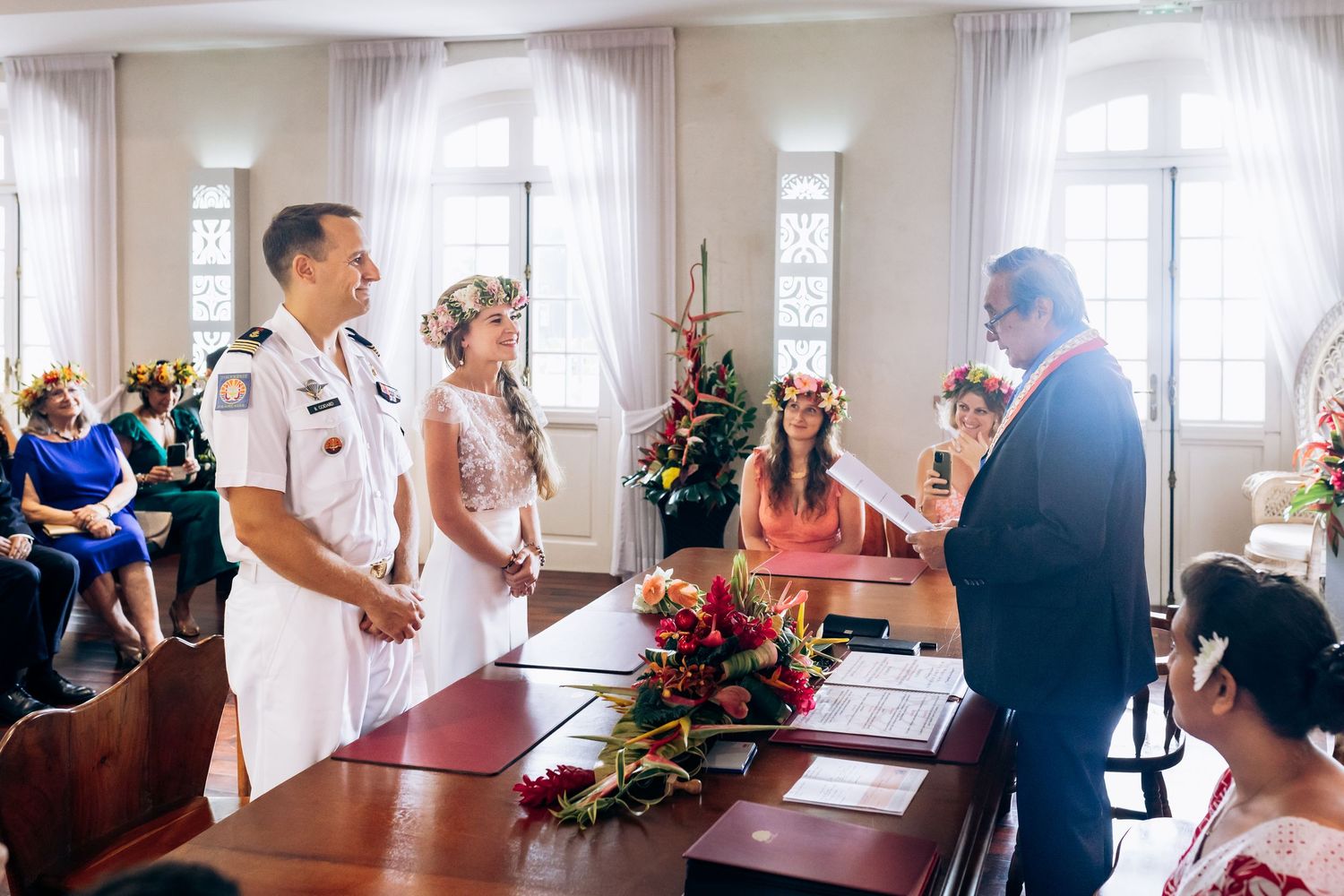 La mariée et le marié se tiennent devant l'officiant lors de la cérémonie de mariage officielle avec un décor floral.