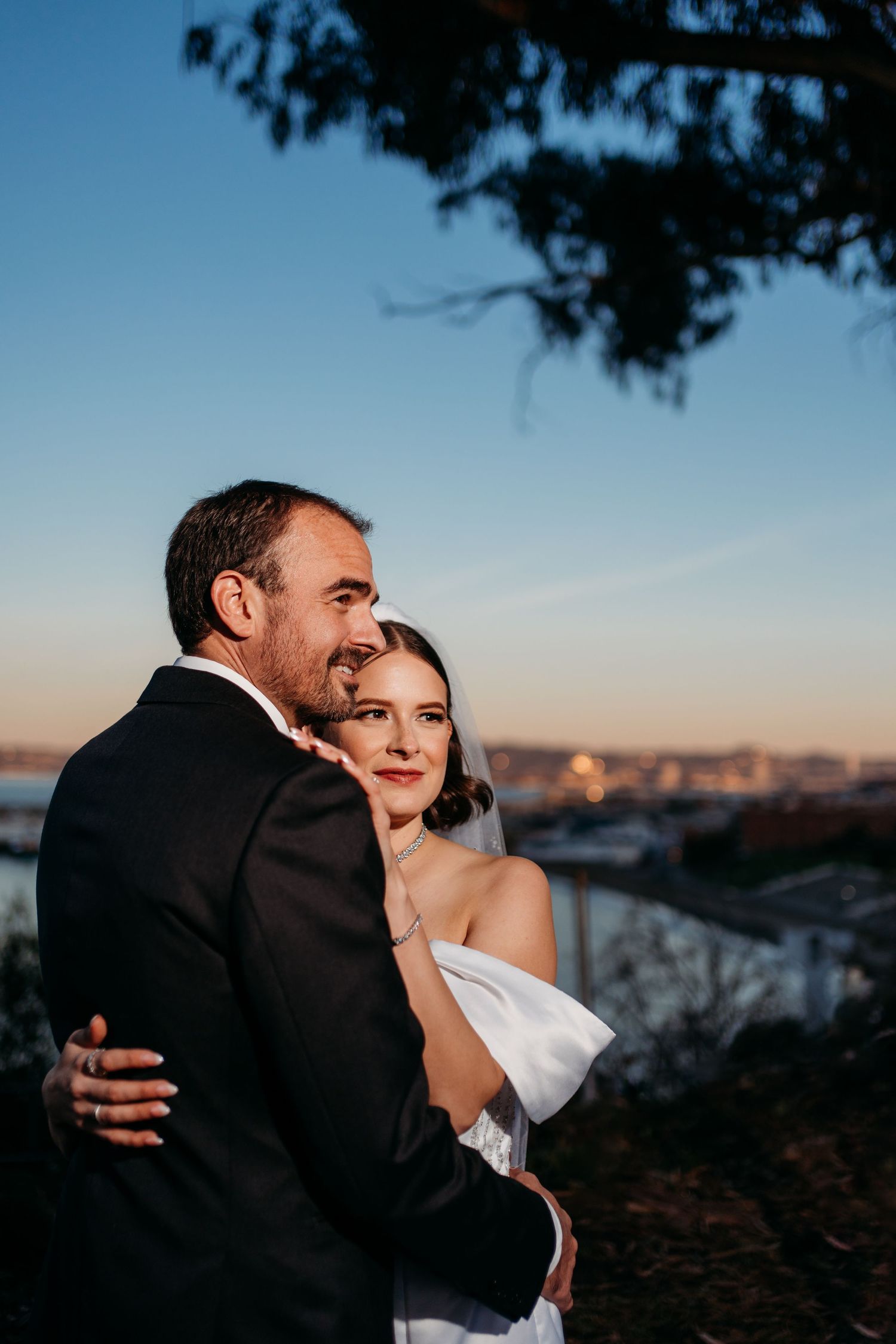 Sunset portrait of a couple embracing with city skyline in background. San Francisco, California.