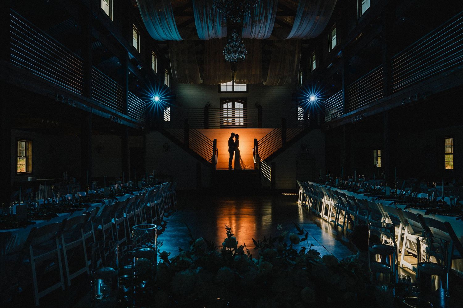Dramatic silhouettes in dark indoor venue with rows of chairs and moody lighting. National, Tennessee