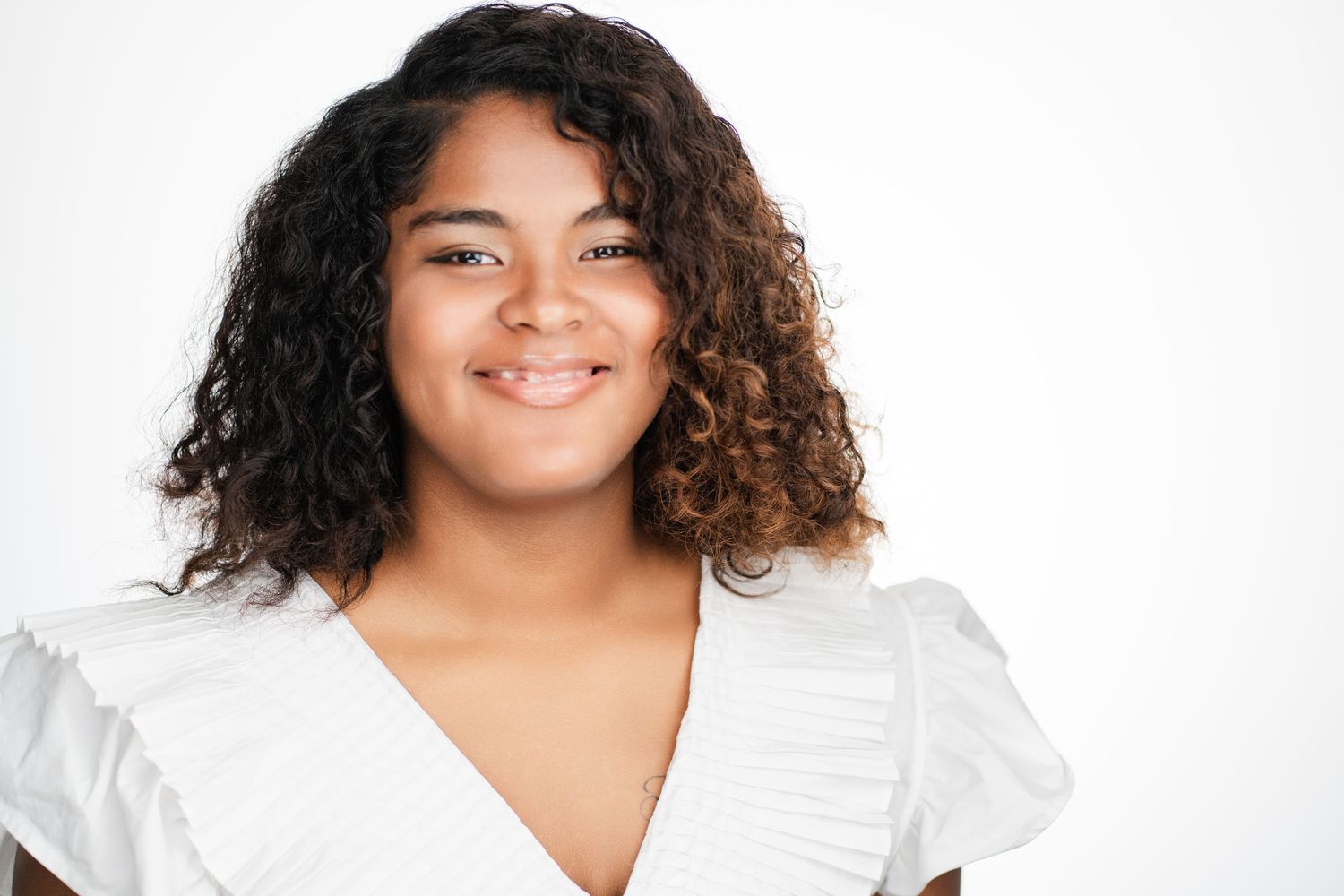 Studio portrait of person in white ruffled top with curly hair against white backdrop. Nashville, Tennessee.
