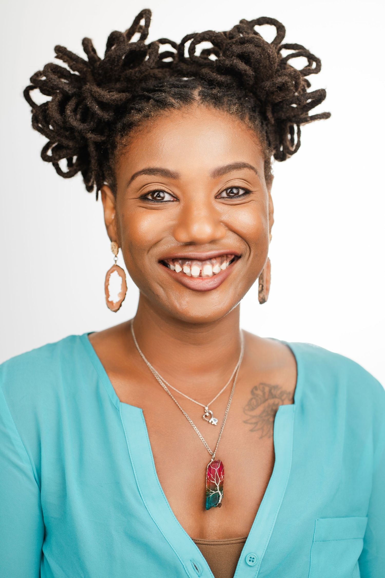 Professional portrait featuring a person with natural hair, hoop earrings, and turquoise top against white background. Nashville, Tennessee.