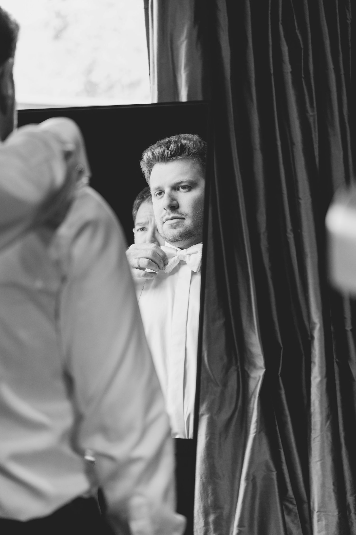 A black and white image of a groom looking in a mirror while getting ready. Nashville, Tennessee.