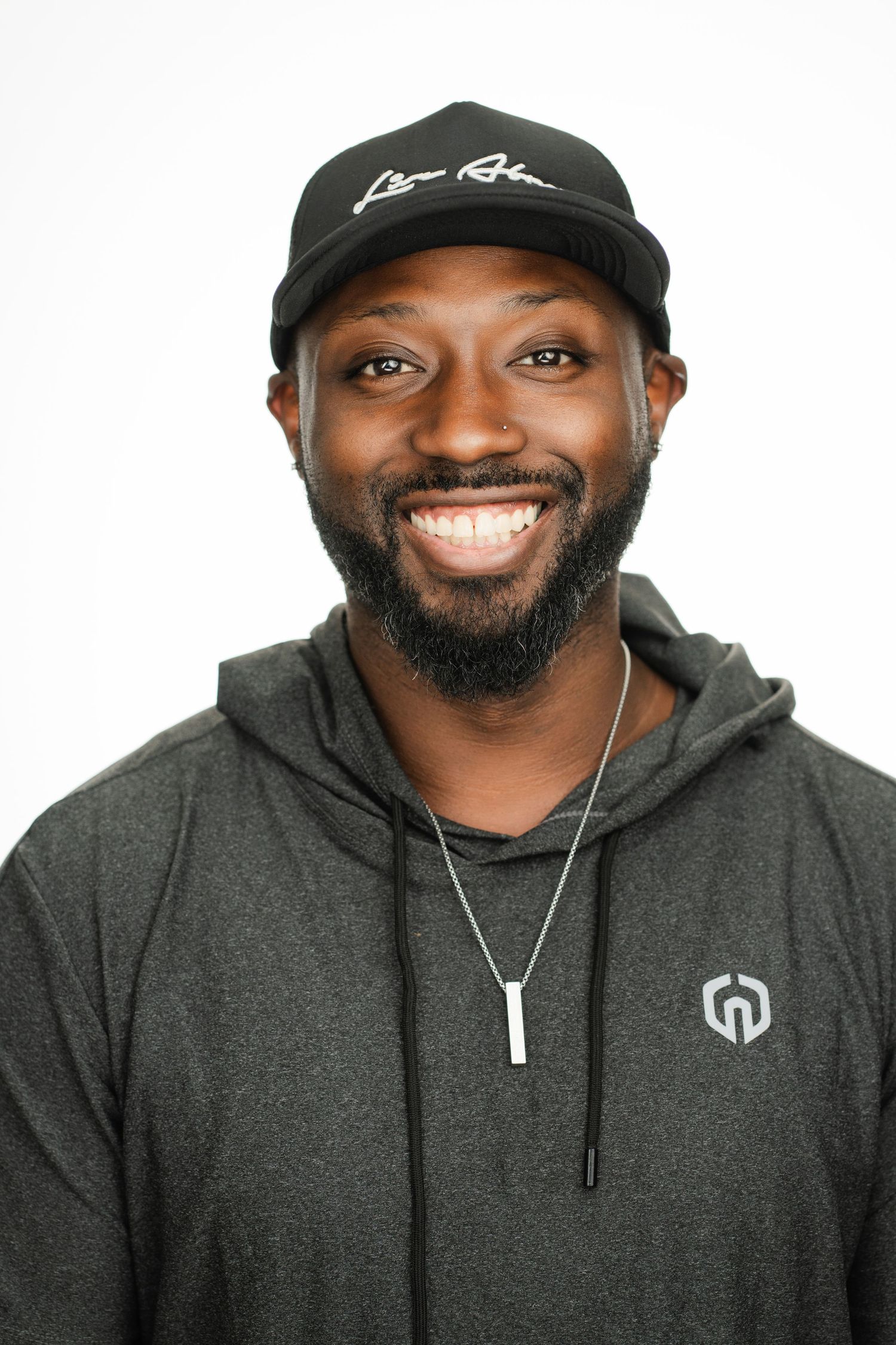 Man in baseball cap and hoodie smiling against white background. Nashville, Tennessee.