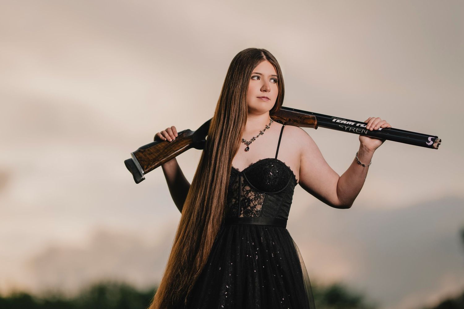 Woman in black dress poses with rifle at sunset. Murfreesboro, Tennessee.