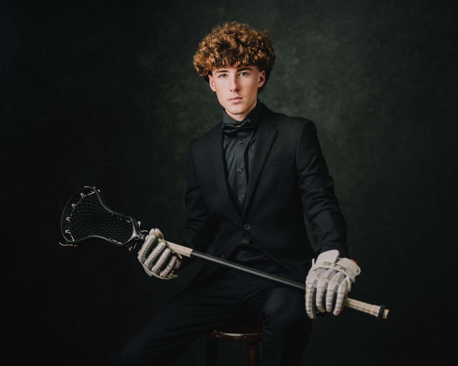 A dramatic studio portrait of someone in formal attire holding a sports equipment. Murfreesboro, Tennessee.