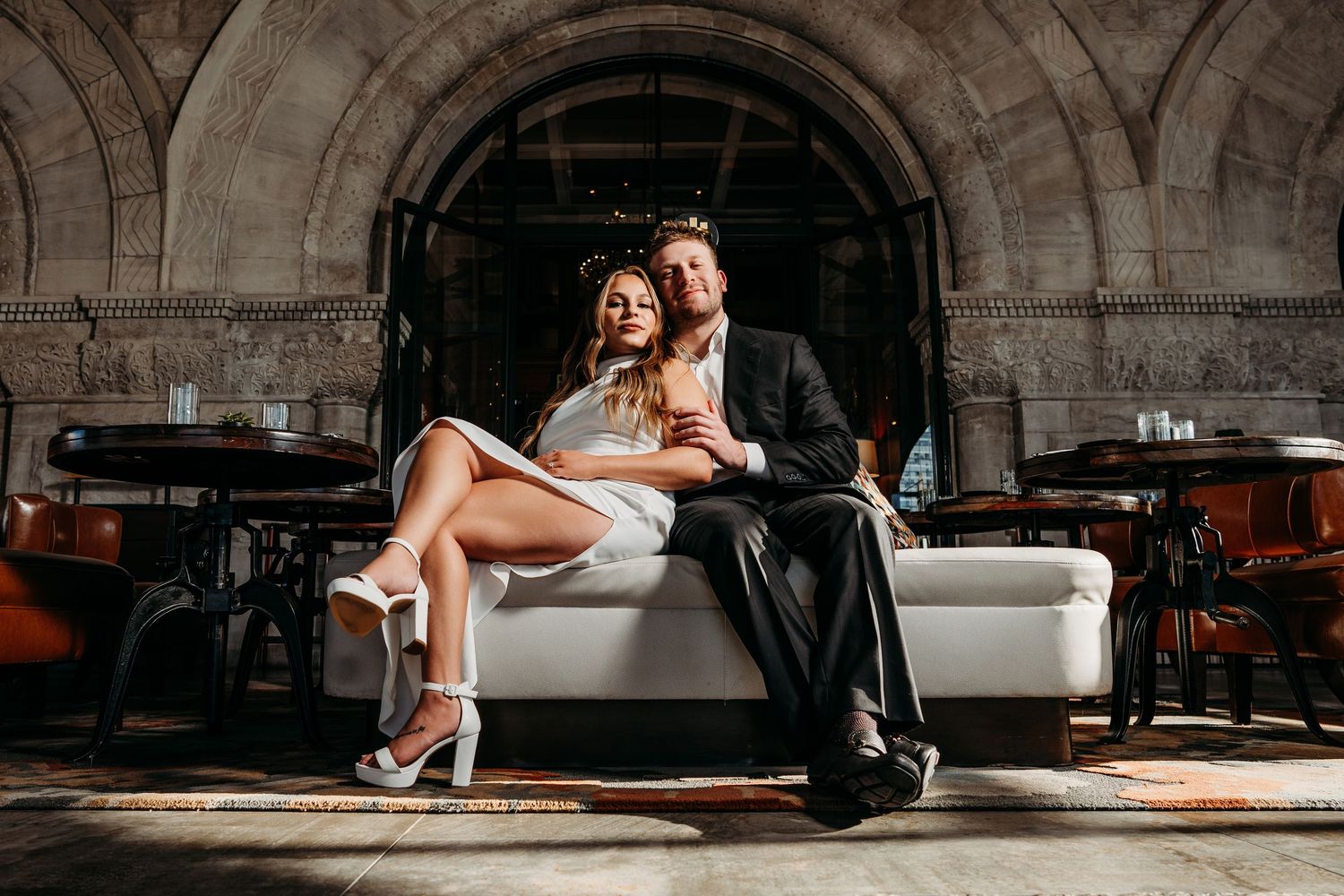 Elegant couple posing on couch in venue with arched stone architecture. Nashville, Tennessee.