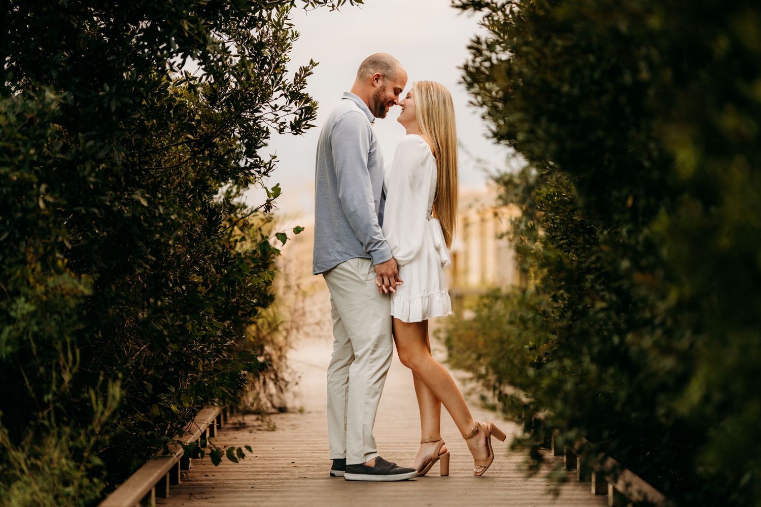 Couple in casual white outfits sharing intimate moment on wooden boardwalk path. Charleston, South Carolina.