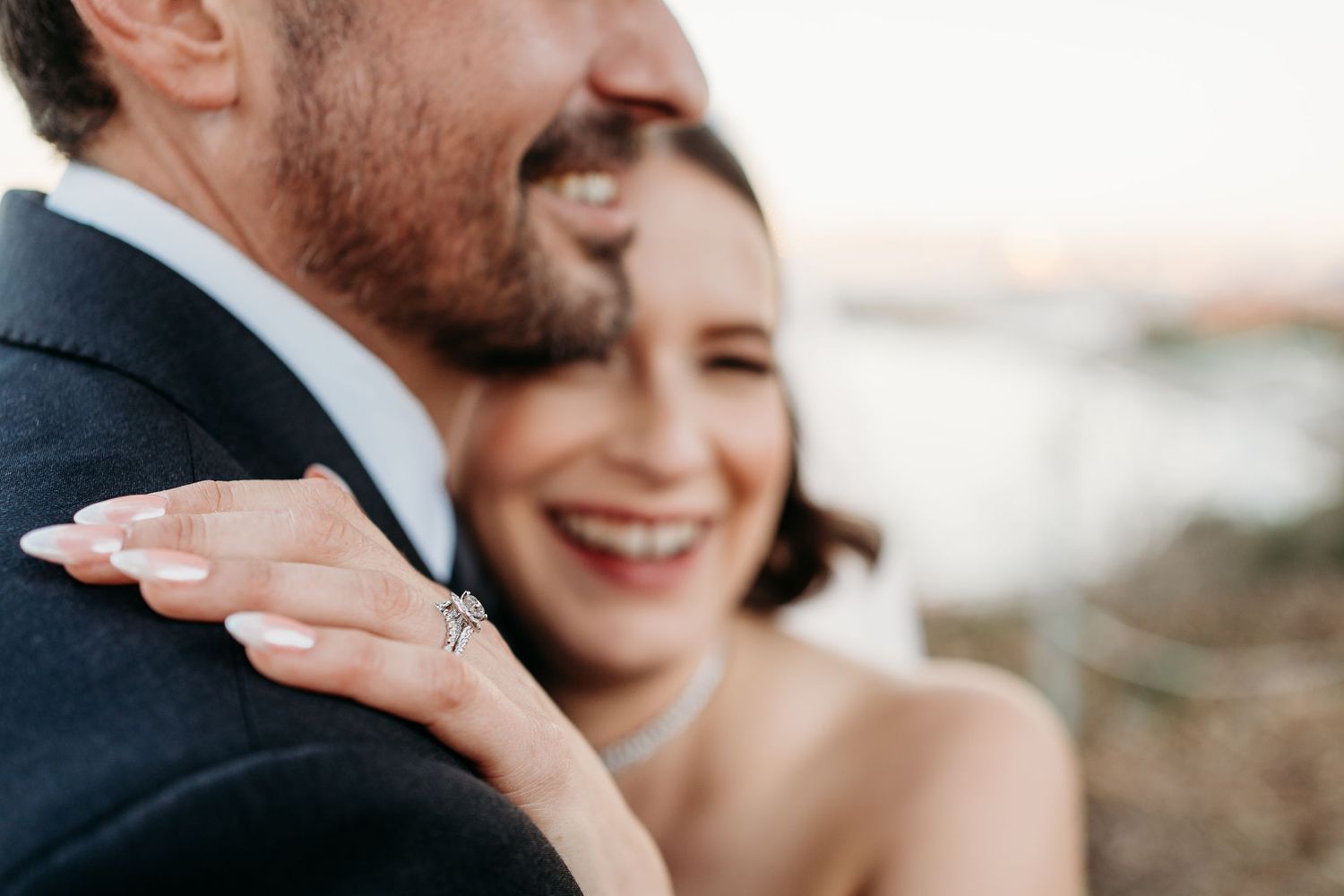 Close-up shot of newlyweds embracing and smiling while showing off the wedding ring. San Francisco, California.