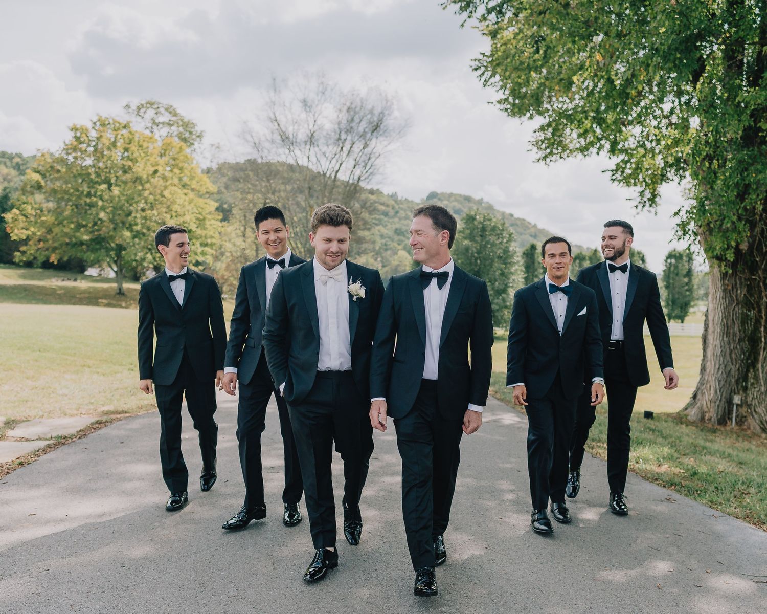 A group of groomsmen in formal attire walking together on a path outdoors. Nashville, Tennessee.