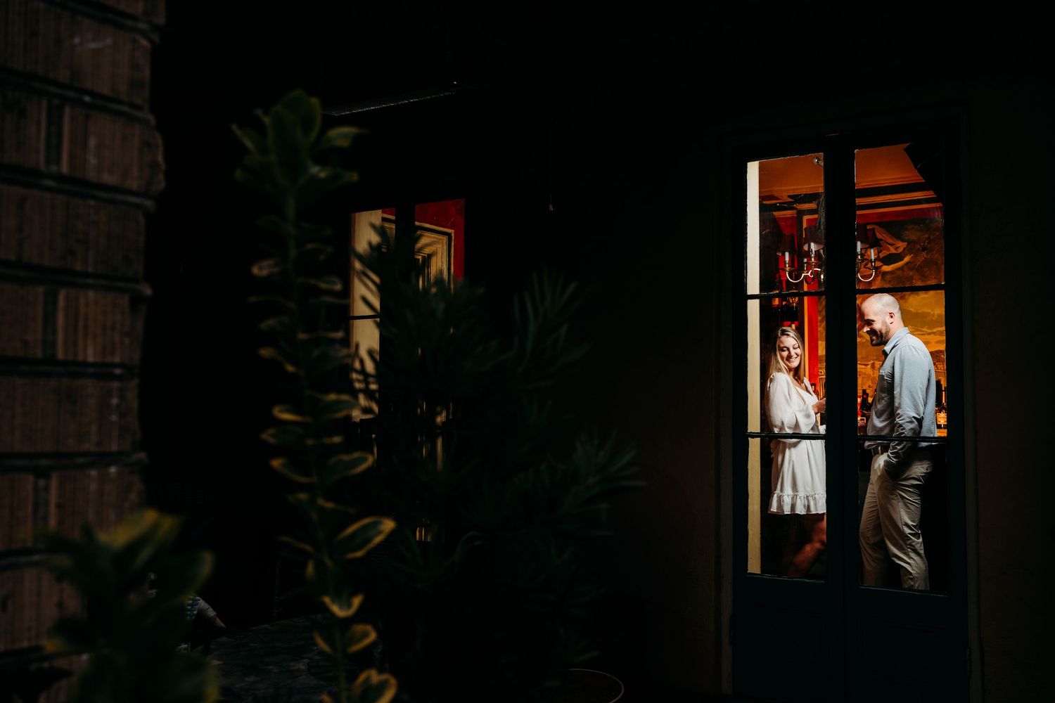 Evening scene through window showing couple in warmly lit interior. Charleston, South Carolina.