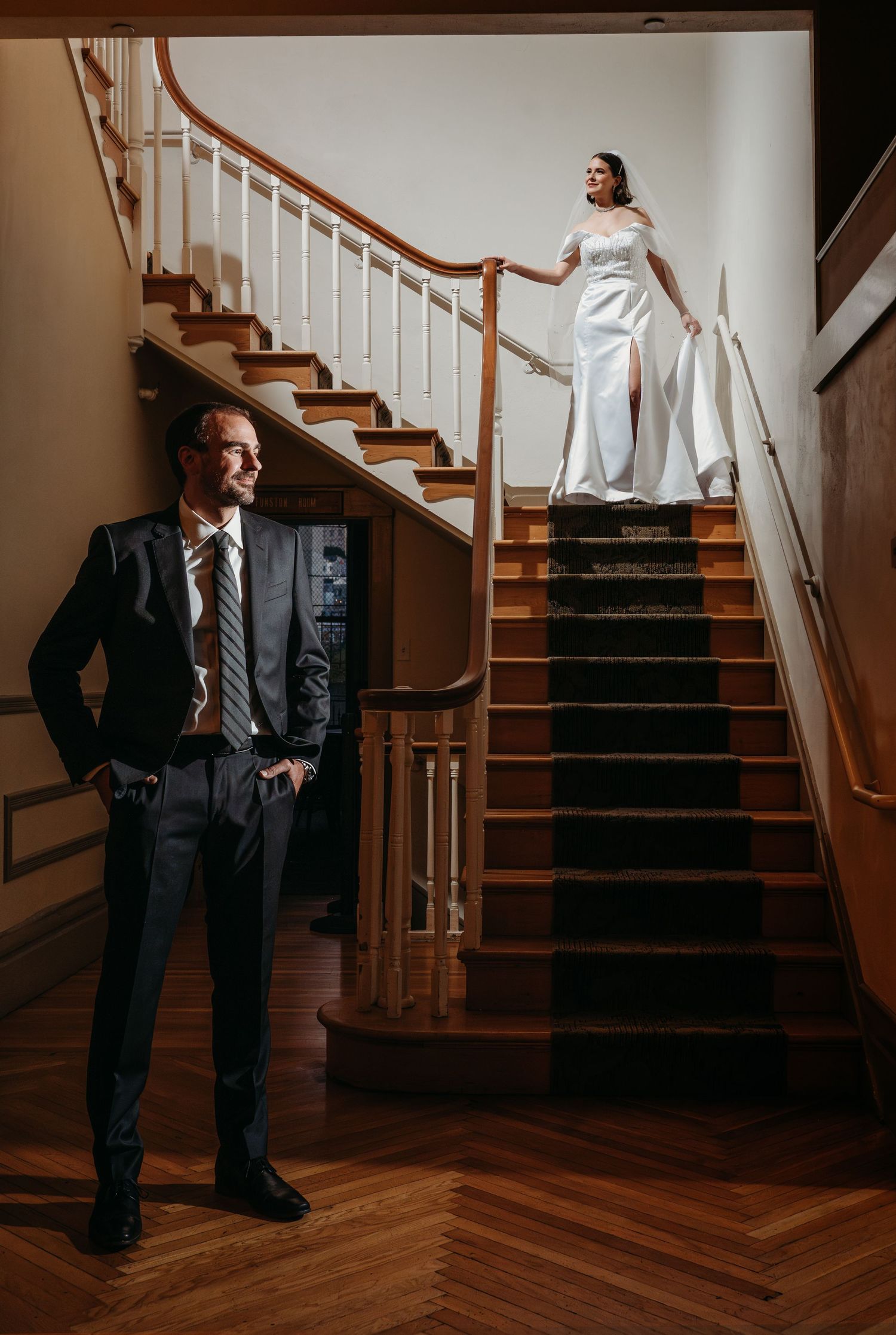 A formal wedding portrait showing a couple posing on an elegant wooden staircase with white walls. San Francisco, California.