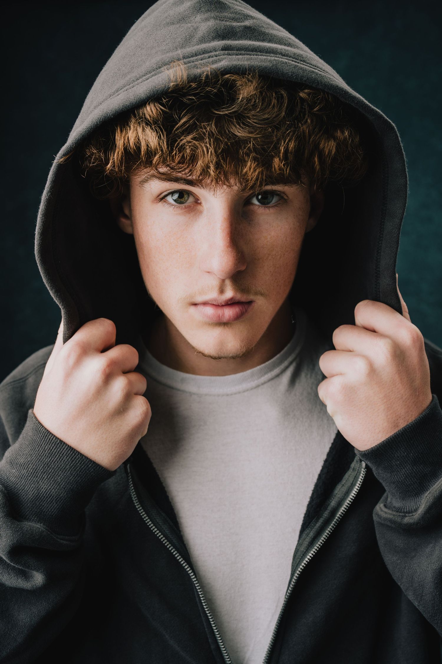 A moody portrait featuring someone in a gray hoodie against a dark background. Murfreesboro, Tennessee.