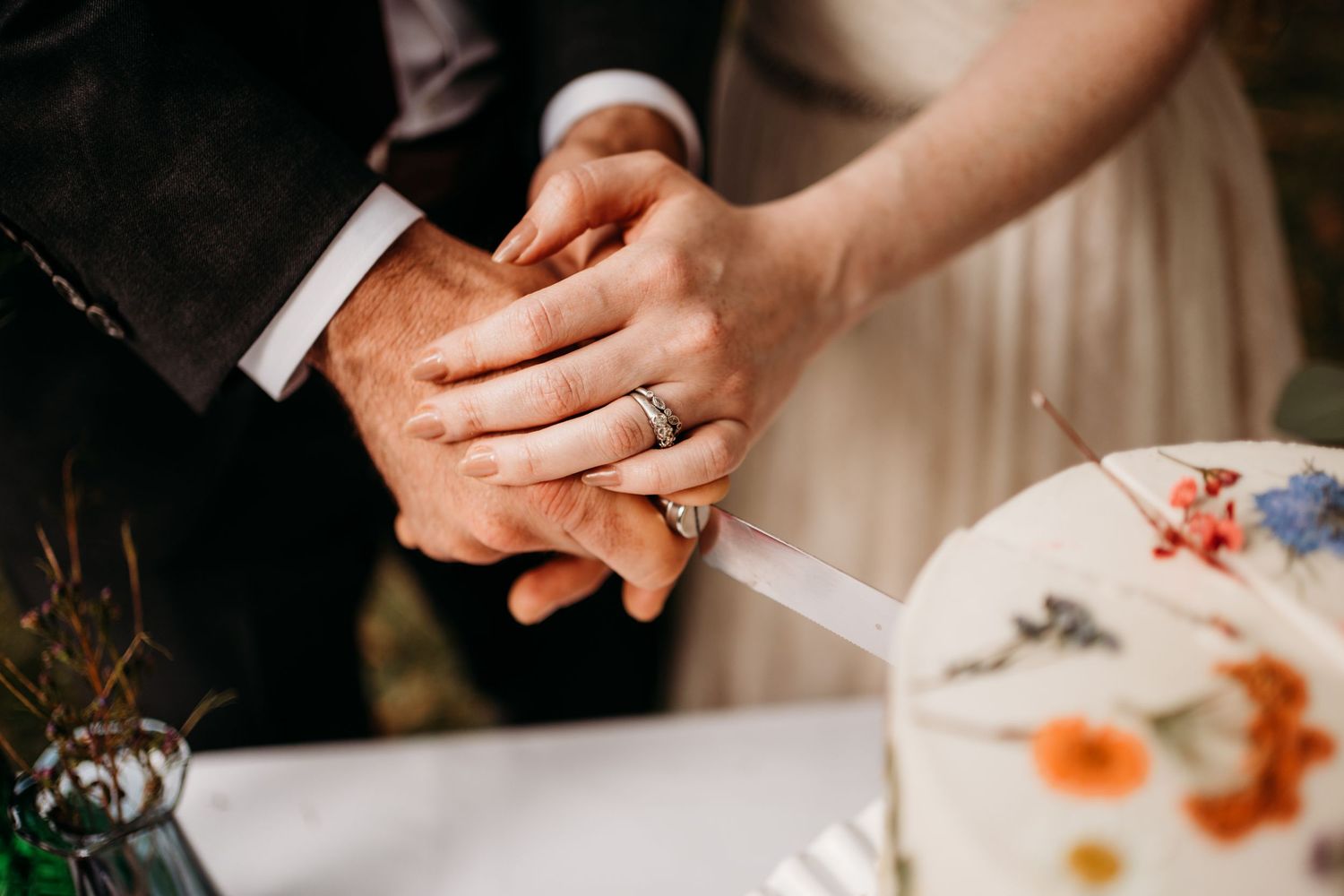 Close up of hands with wedding rings during ceremony with floral decorations. Nashville, Tennessee.