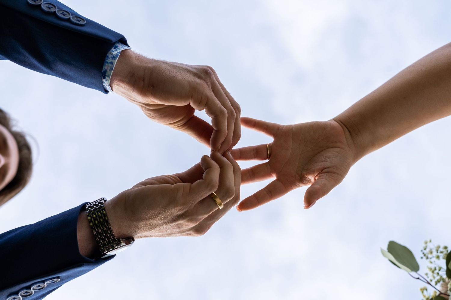 Close-up shot of hands exchanging wedding rings against a bright sky background. Nashville, Tennessee.