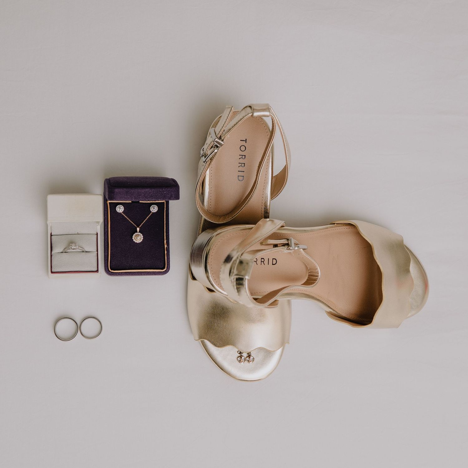 Wedding accessories including rings, shoes and jewelry box arranged on white surface. Nashville, Tennessee.