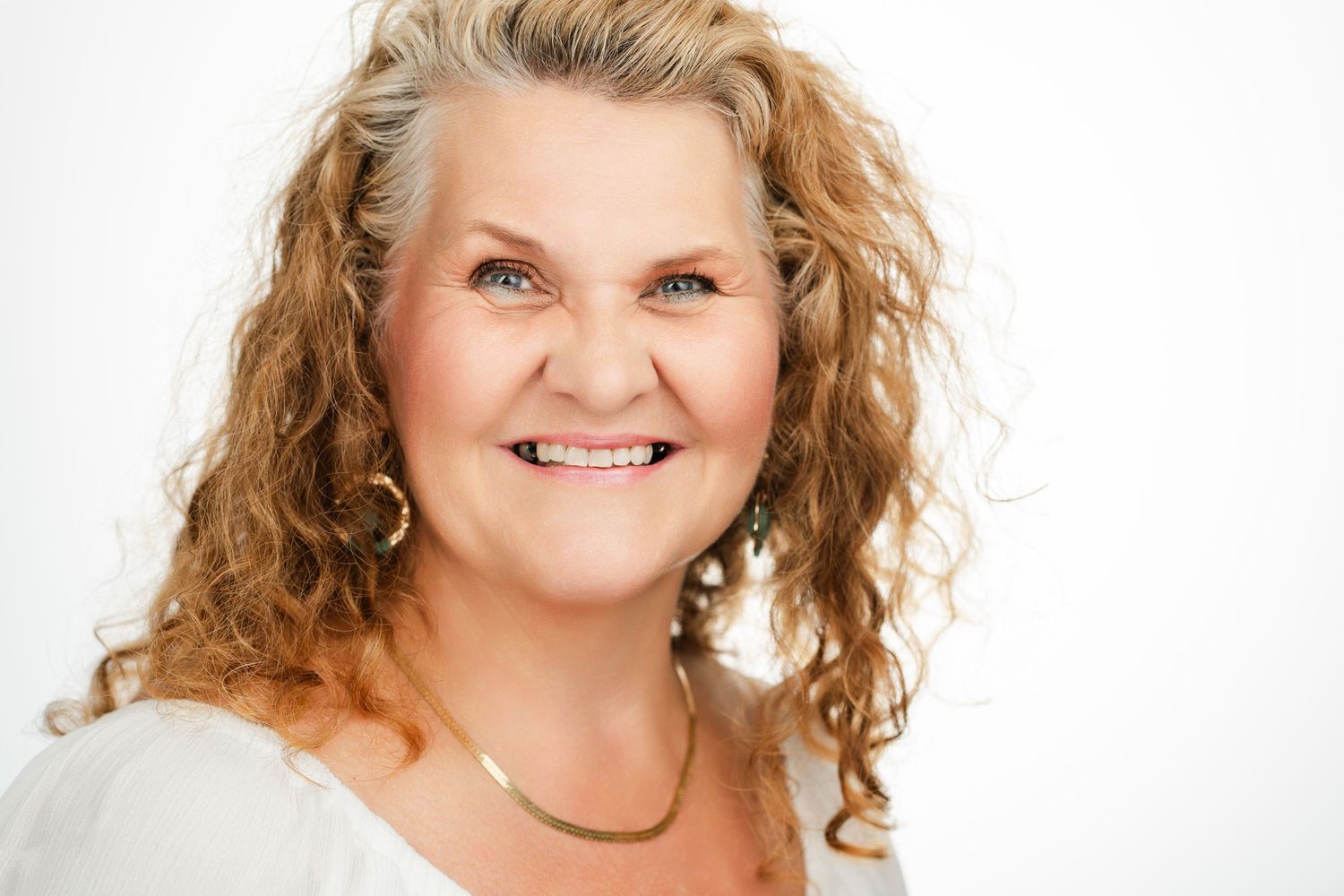 Portrait of person with curly blonde hair and bright smile wearing white top. Nashville, Tennessee.