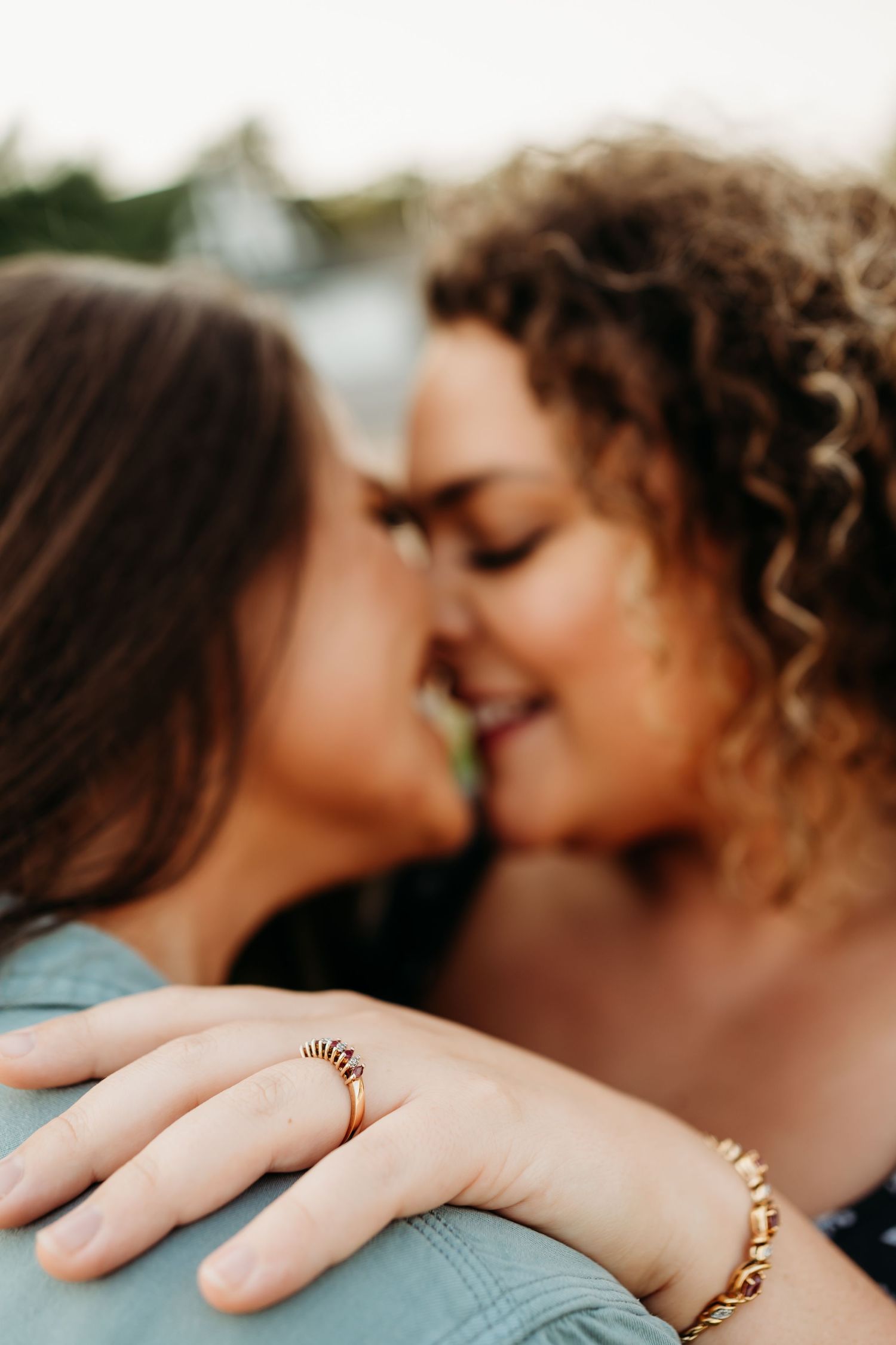 Close up of a diamond engagement ring shown while two people share an intimate moment. Nashville, Tennessee.