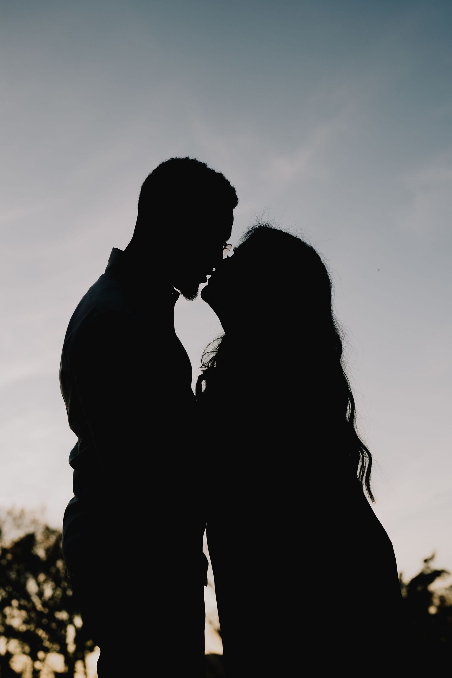 A silhouetted couple shares an intimate moment against a dusky sky. Nashville, Tennessee.