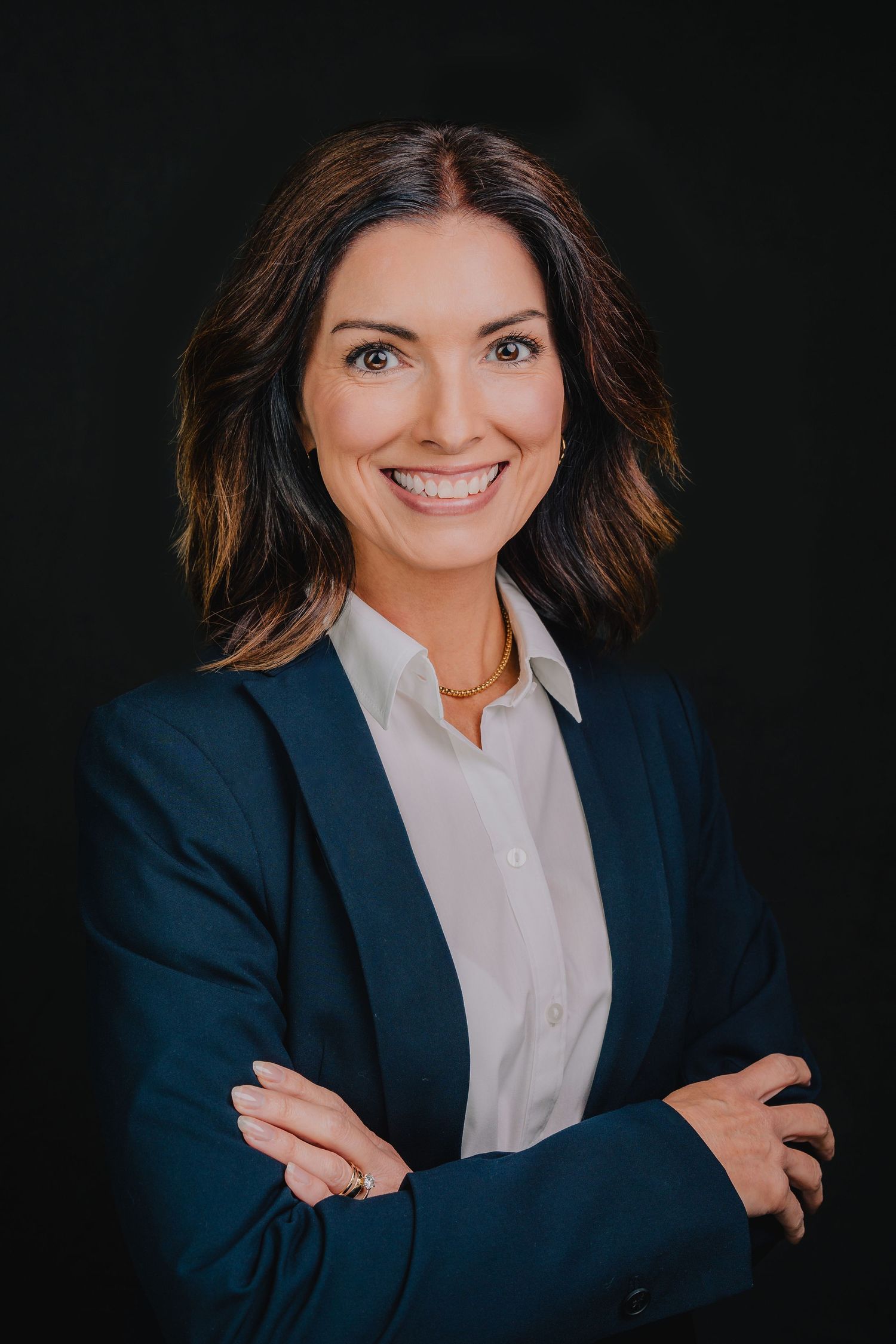 Professional headshot of someone in navy blazer and white shirt against dark background. Nashville, Tennessee.