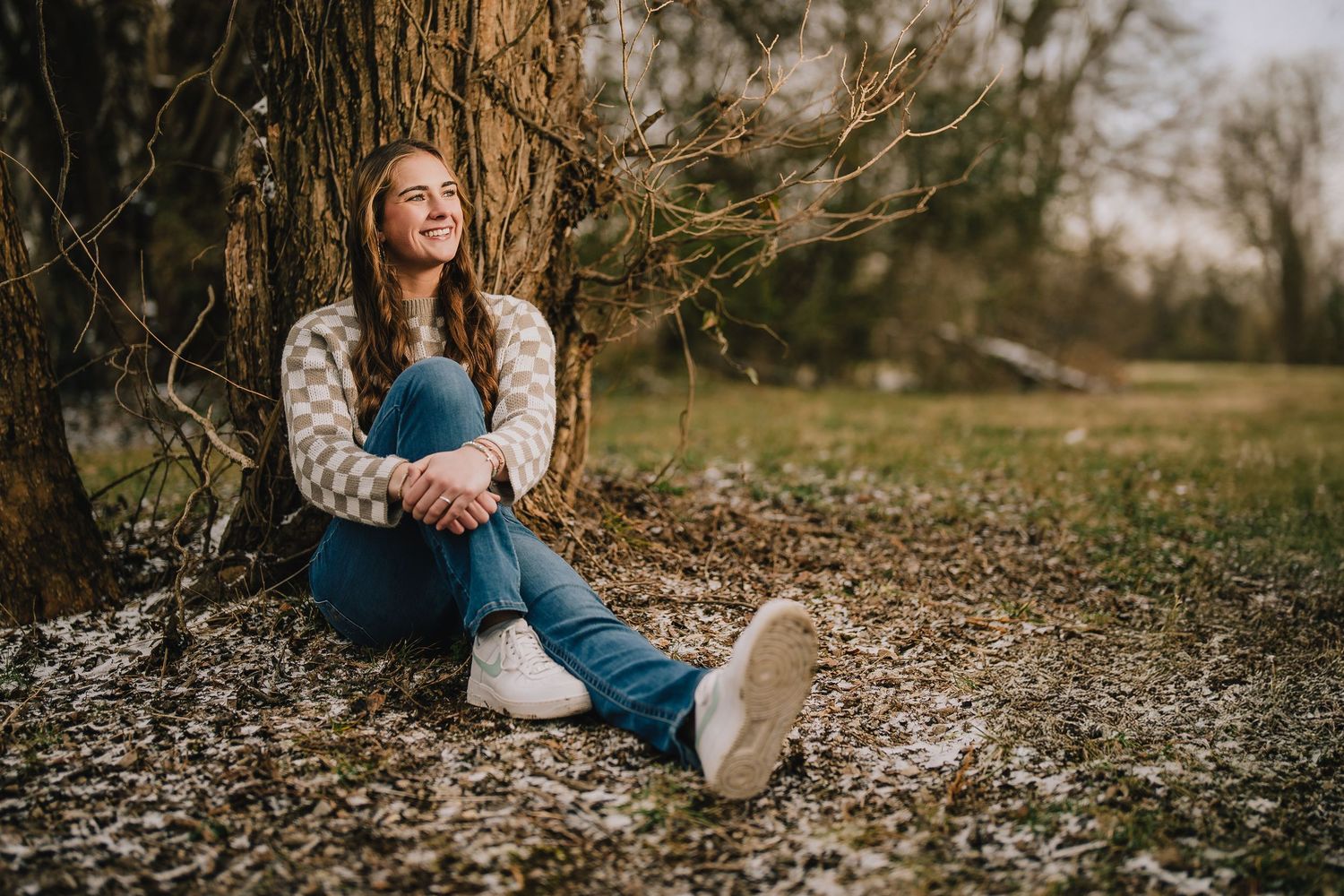 Casual outdoor portrait against tree trunk on fallen autumn leaves wearing denim and sweater. Nashville, Tennessee.