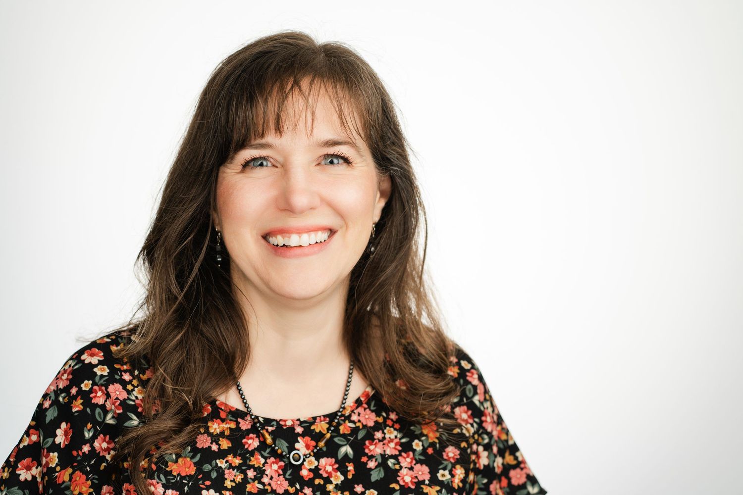 Cheerful woman in floral print dress against white background. Nashville, Tennessee.