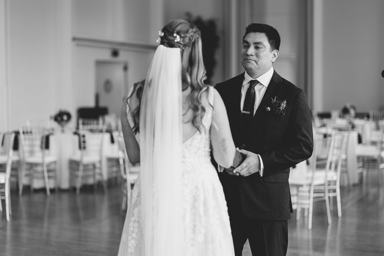 A couple shares their first dance in an elegant ballroom with white chairs. Milwaukee, Wisconsin.