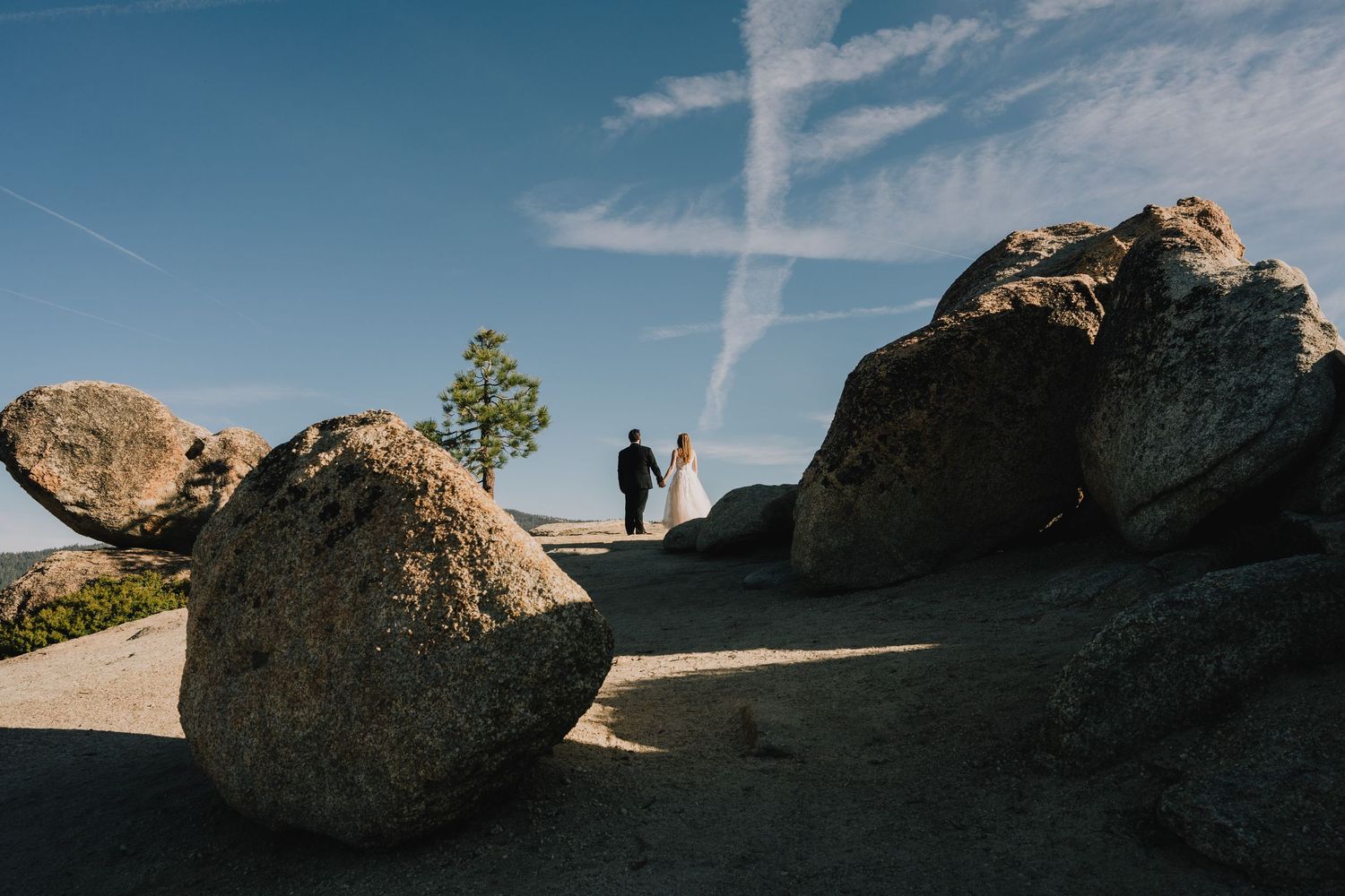 Silhouetted couple walking among large boulders against blue sky. Yosemite national Park California.