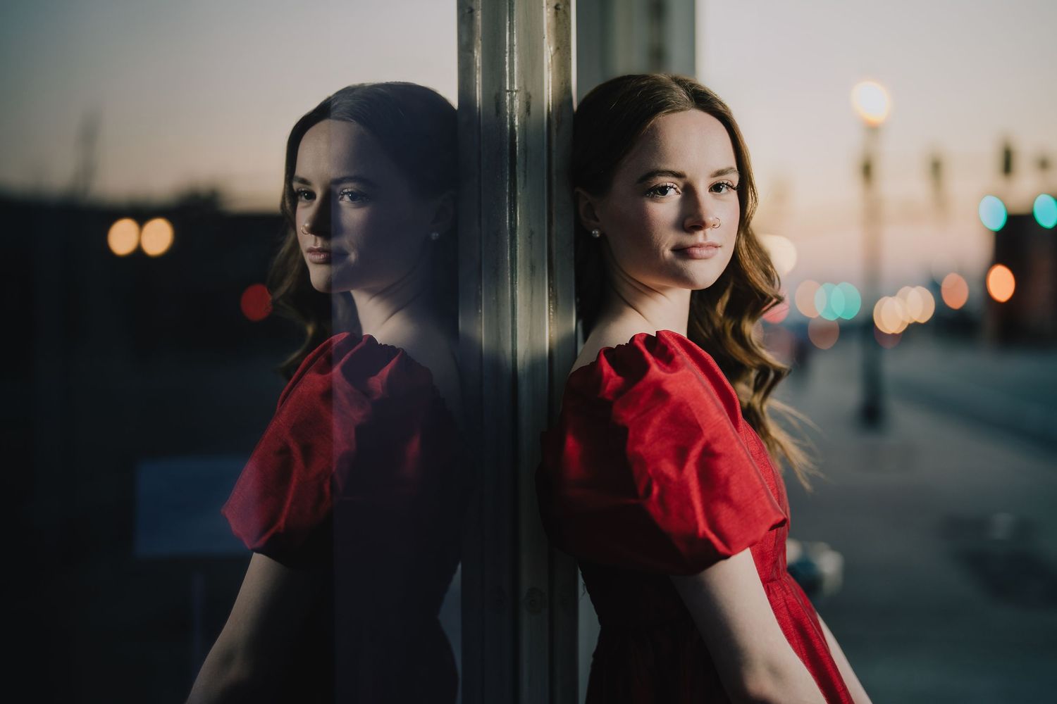 Moody evening portrait in red dress reflected in window glass. Nashville, Tennessee.