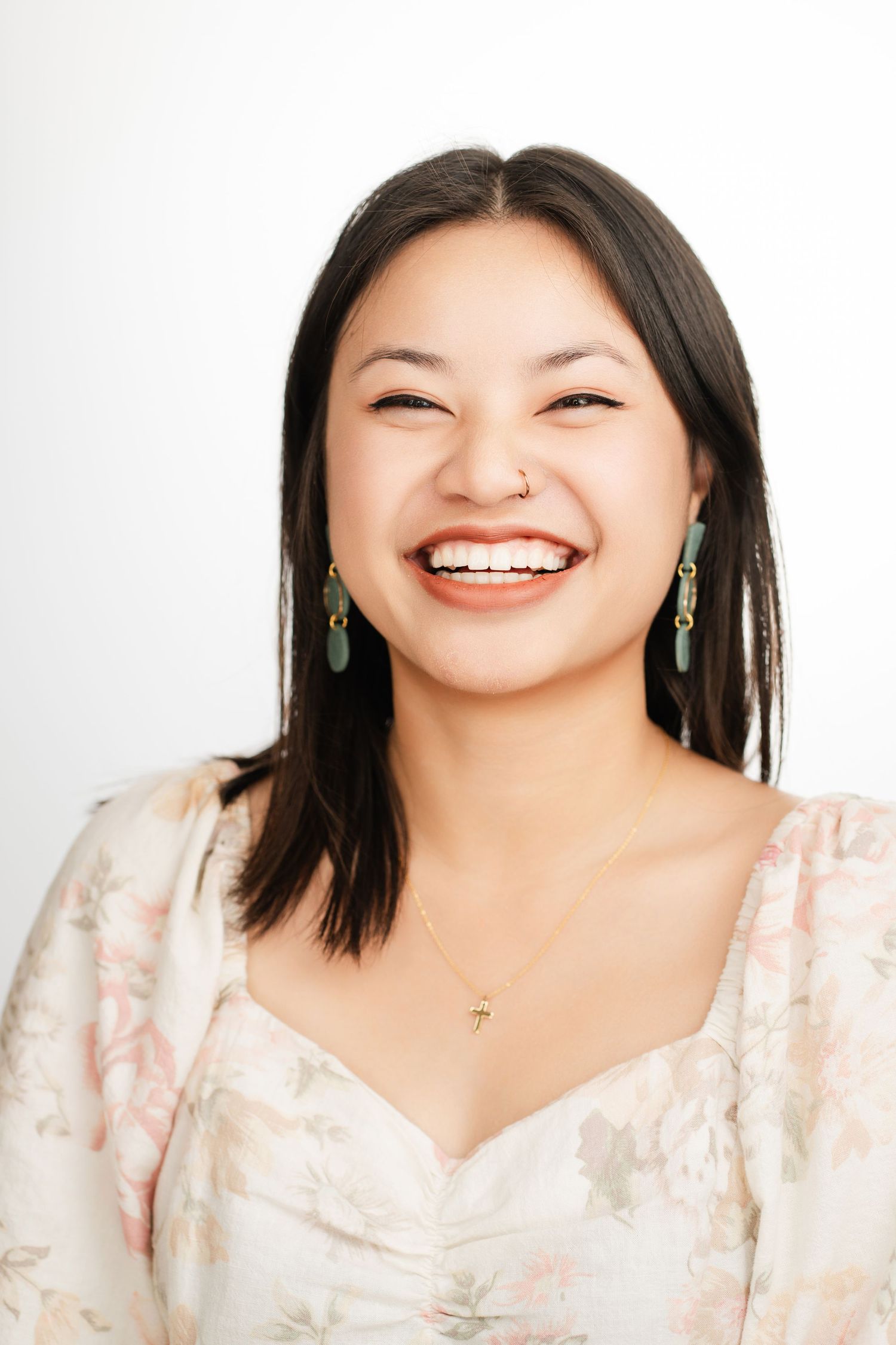Professional portrait of a person in a floral dress with dangling earrings against white background. Nashville, Tennessee.