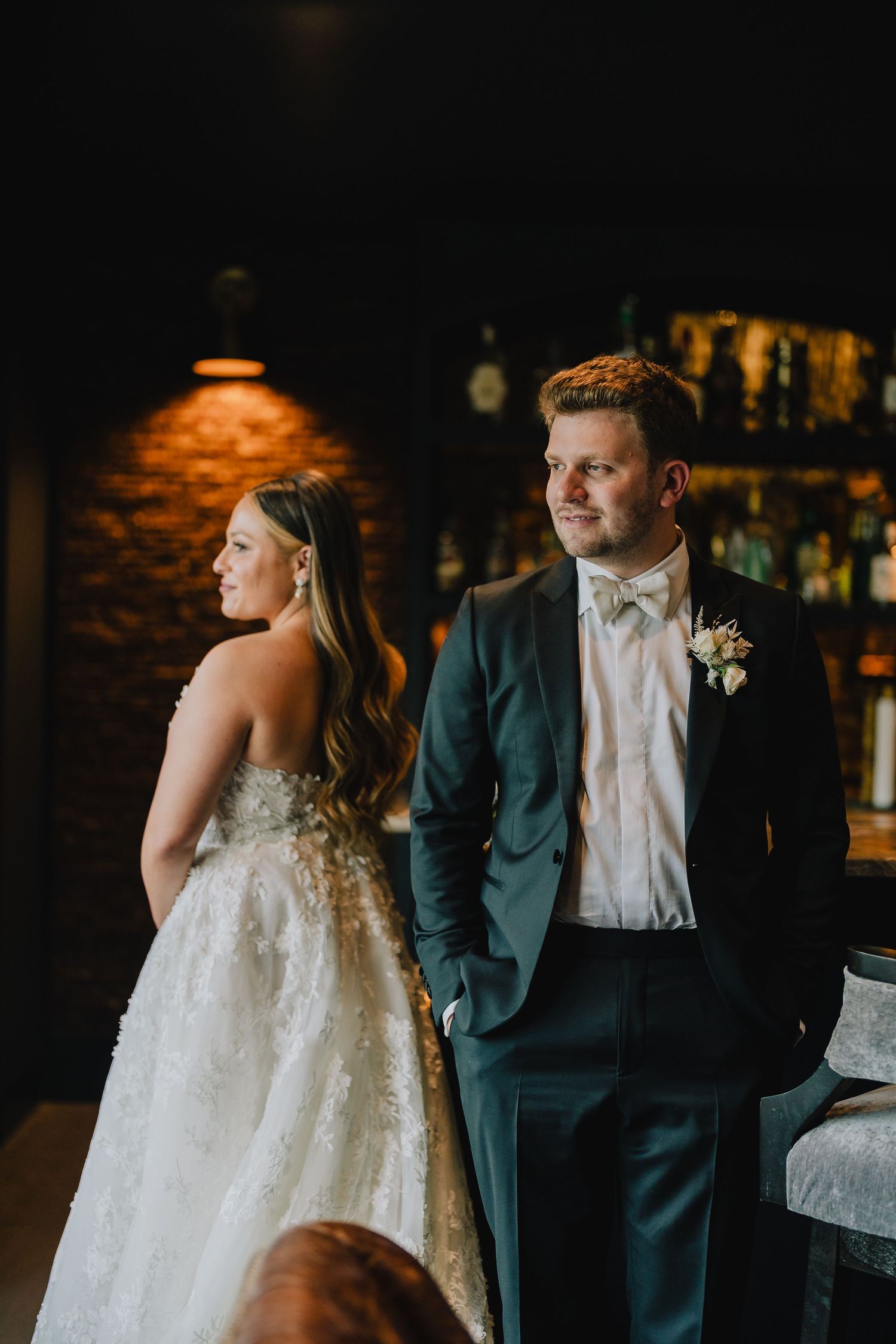 A bride and groom share a moment in front of a rustic brick wall and bar setting. Nashville, Tennessee.