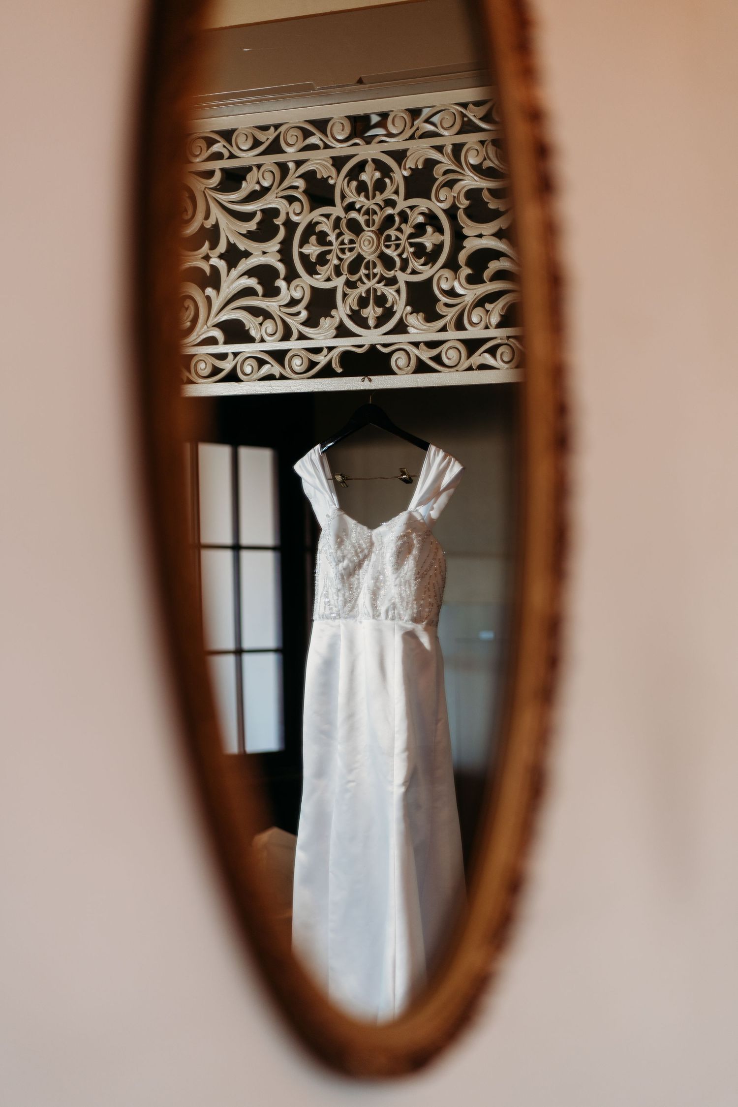 White wedding dress reflection in oval vintage mirror with ornate decorative frame. San Francisco, California.