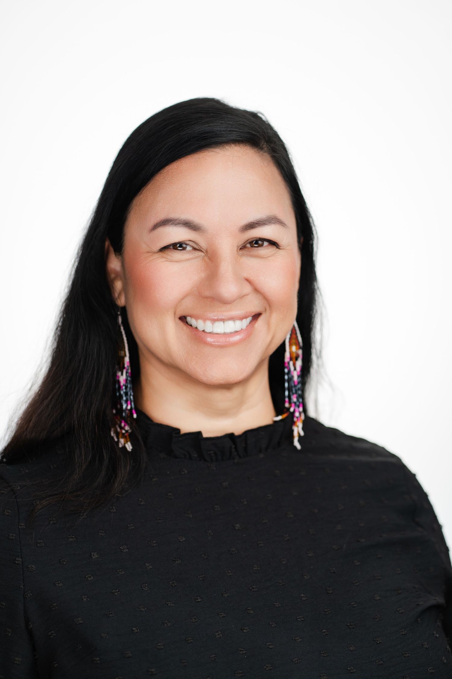 Professional portrait of a person with long dark hair wearing black top and colorful earrings. Nashville, Tennessee.
