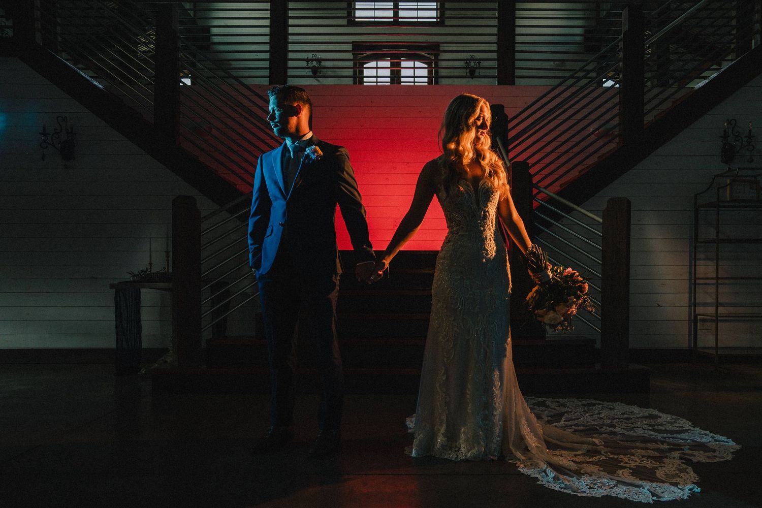 Silhouette of a couple holding hands in a dramatically lit warehouse with red backlighting. Nashville, Tennessee.