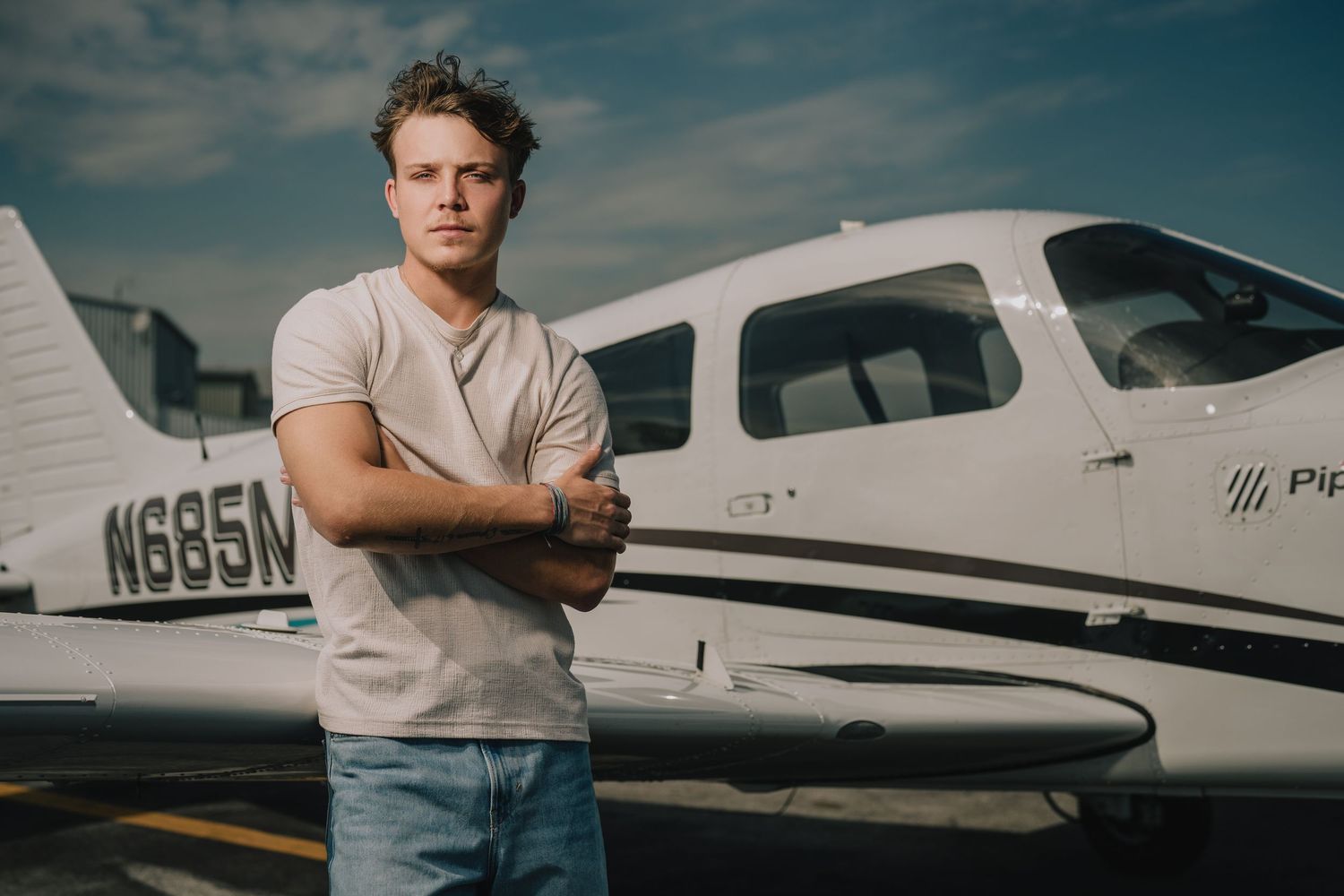 A person stands confidently next to a small private aircraft on a sunny day at an airfield. Murfreesboro, Tennessee.