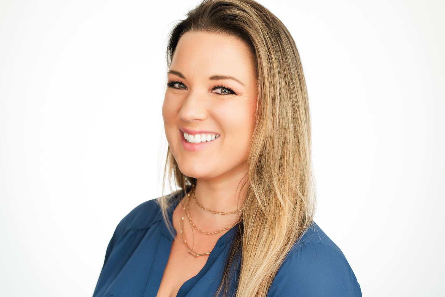Professional headshot of someone with blonde hair wearing a blue top against white background. Nashville, Tennessee.