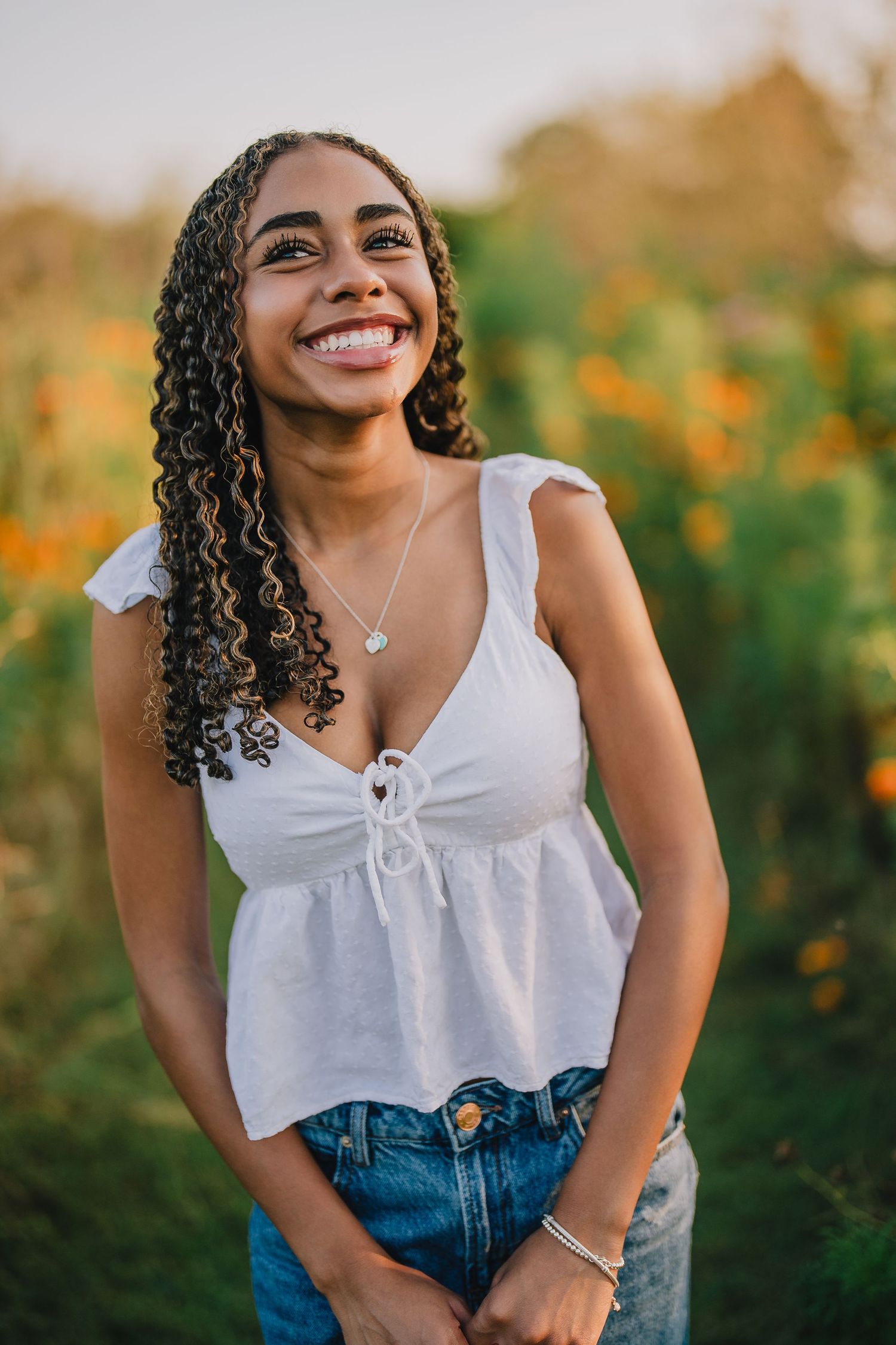 Portrait of a smiling person in a white top and jeans against a summer garden background. Nashville, Tennessee.