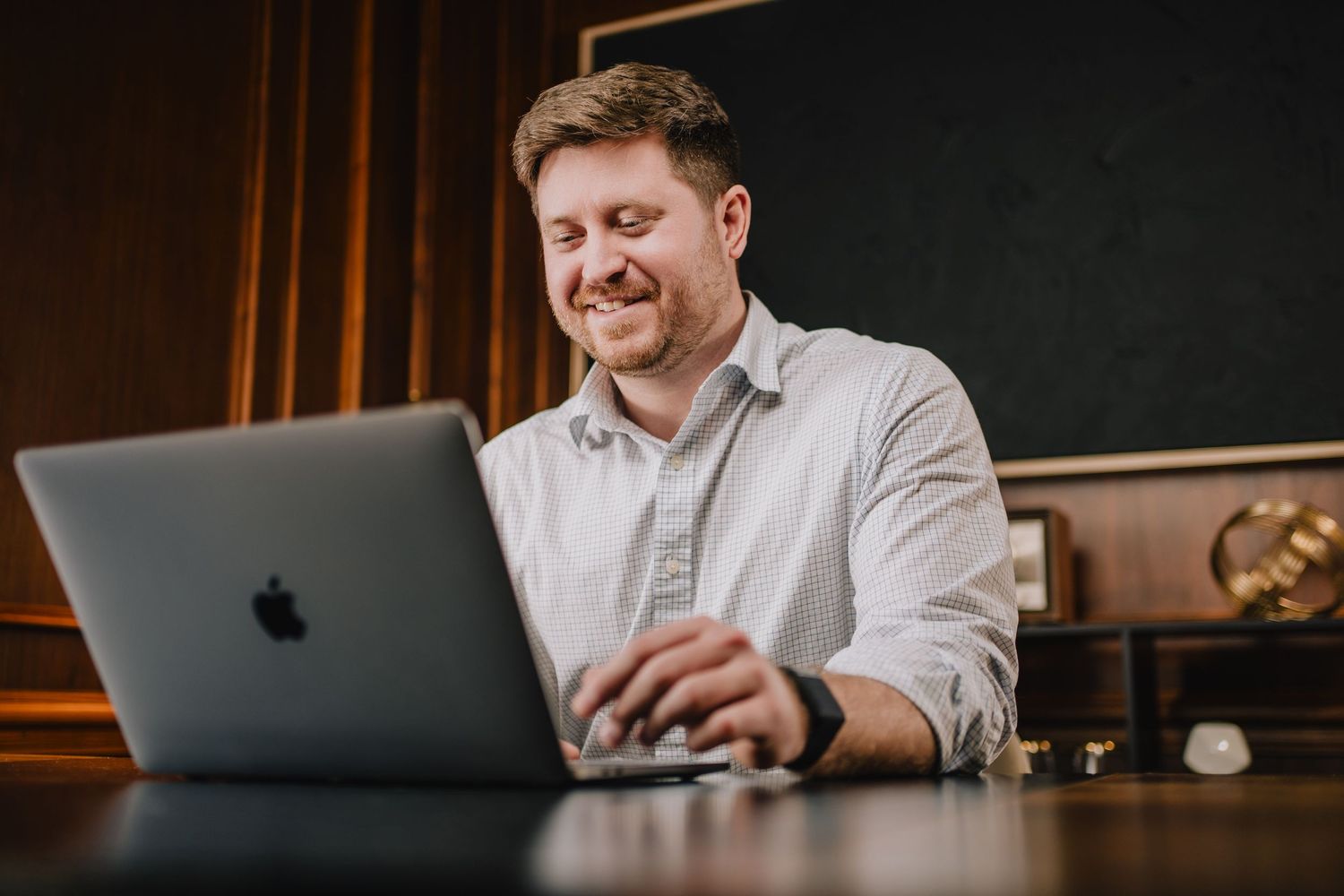Person working on MacBook laptop in office setting with warm lighting. Nashville, Tennessee.