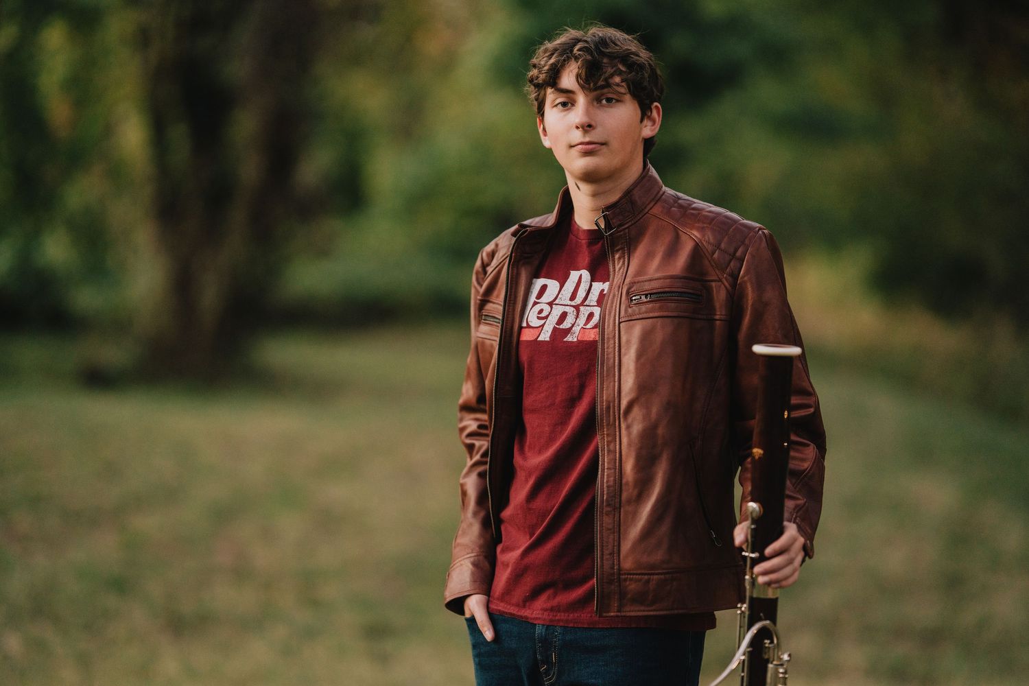 Casual outdoor portrait of someone wearing brown leather jacket and graphic tee in natural setting. Nashville, Tennessee.