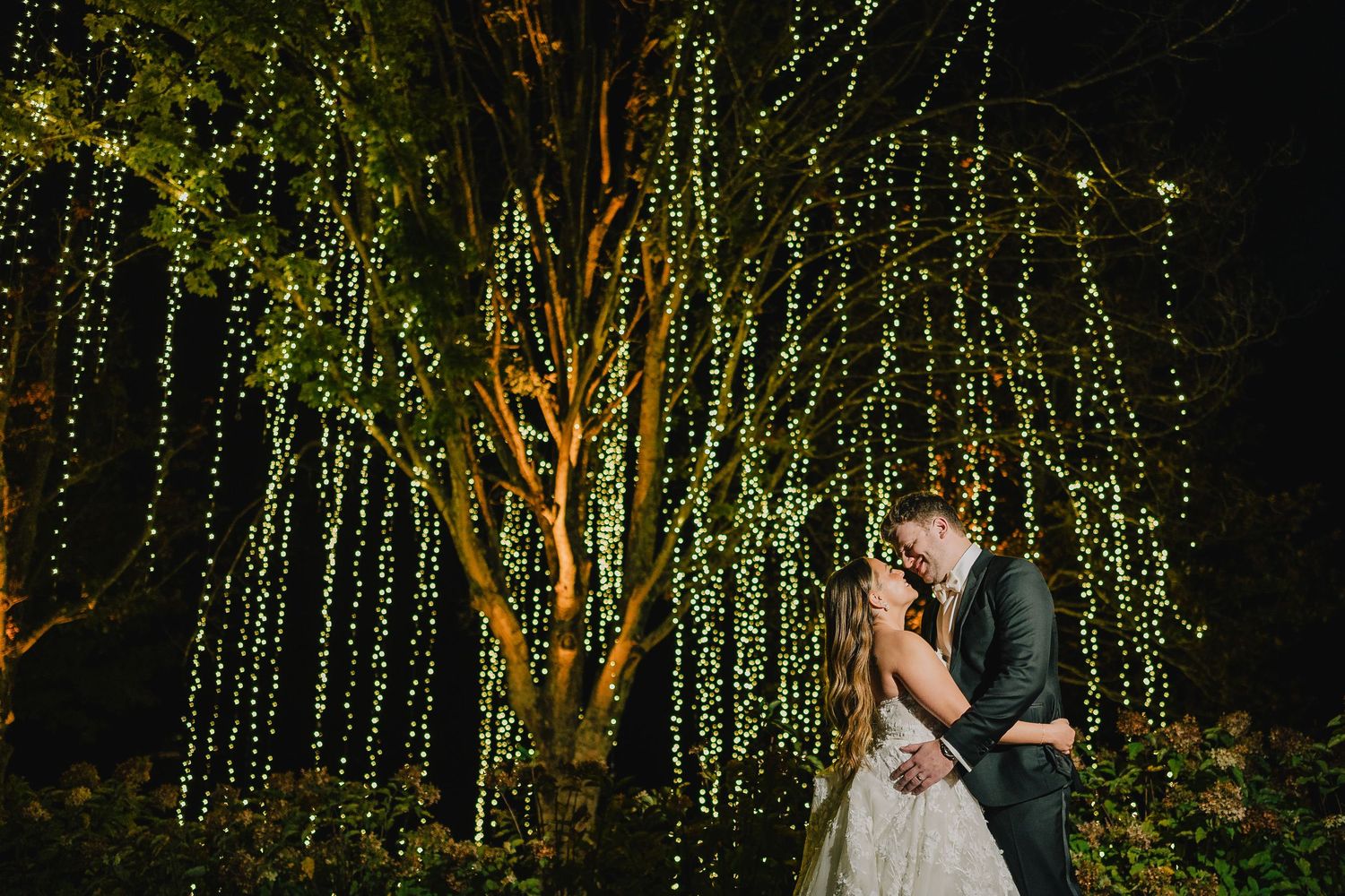 A romantic nighttime wedding photo under trees decorated with hanging fairy lights. Nashville, Tennessee.