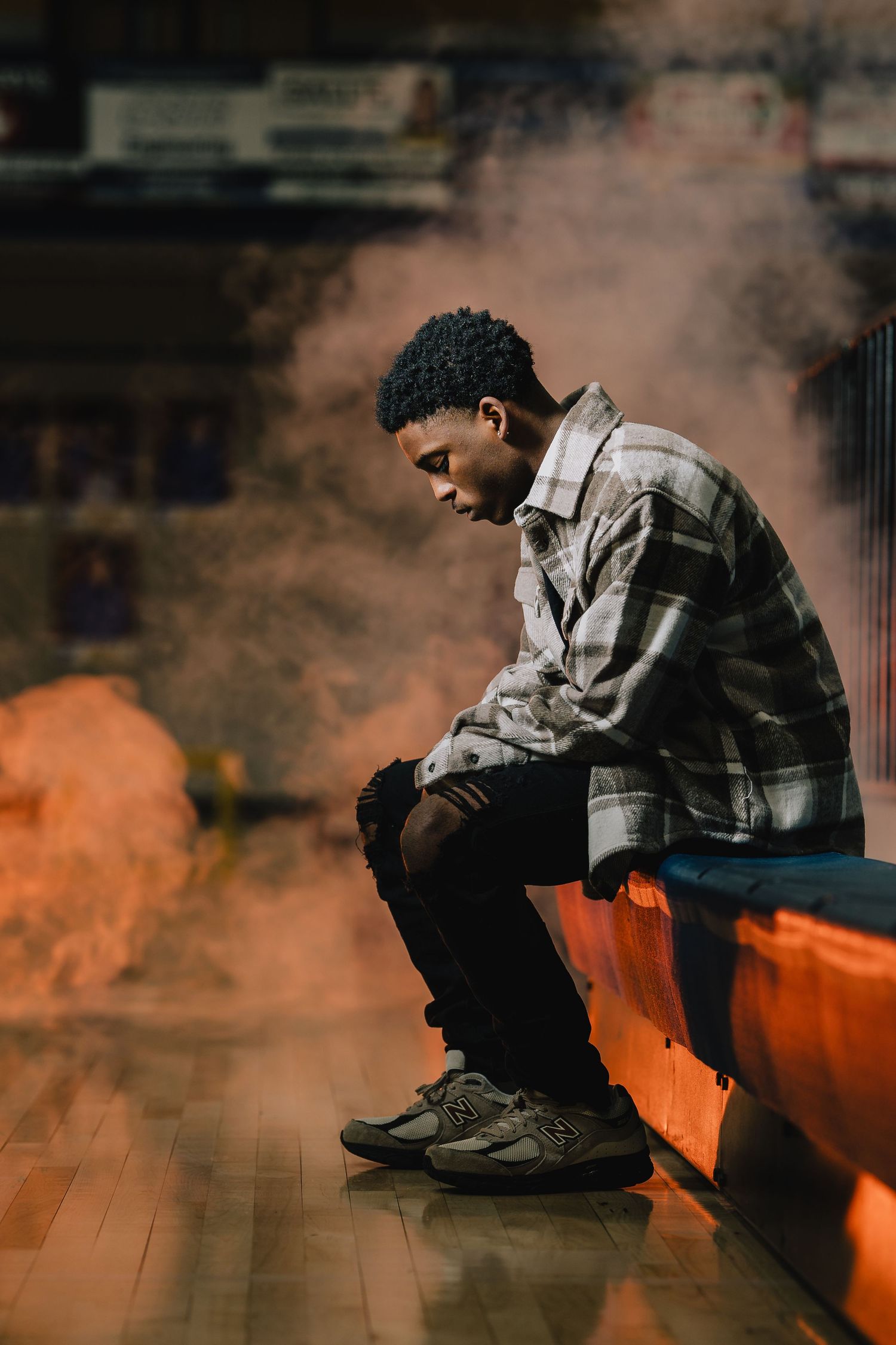 Atmospheric portrait of person sitting on orange bench surrounded by smoke effects. Nashville, Tennessee.