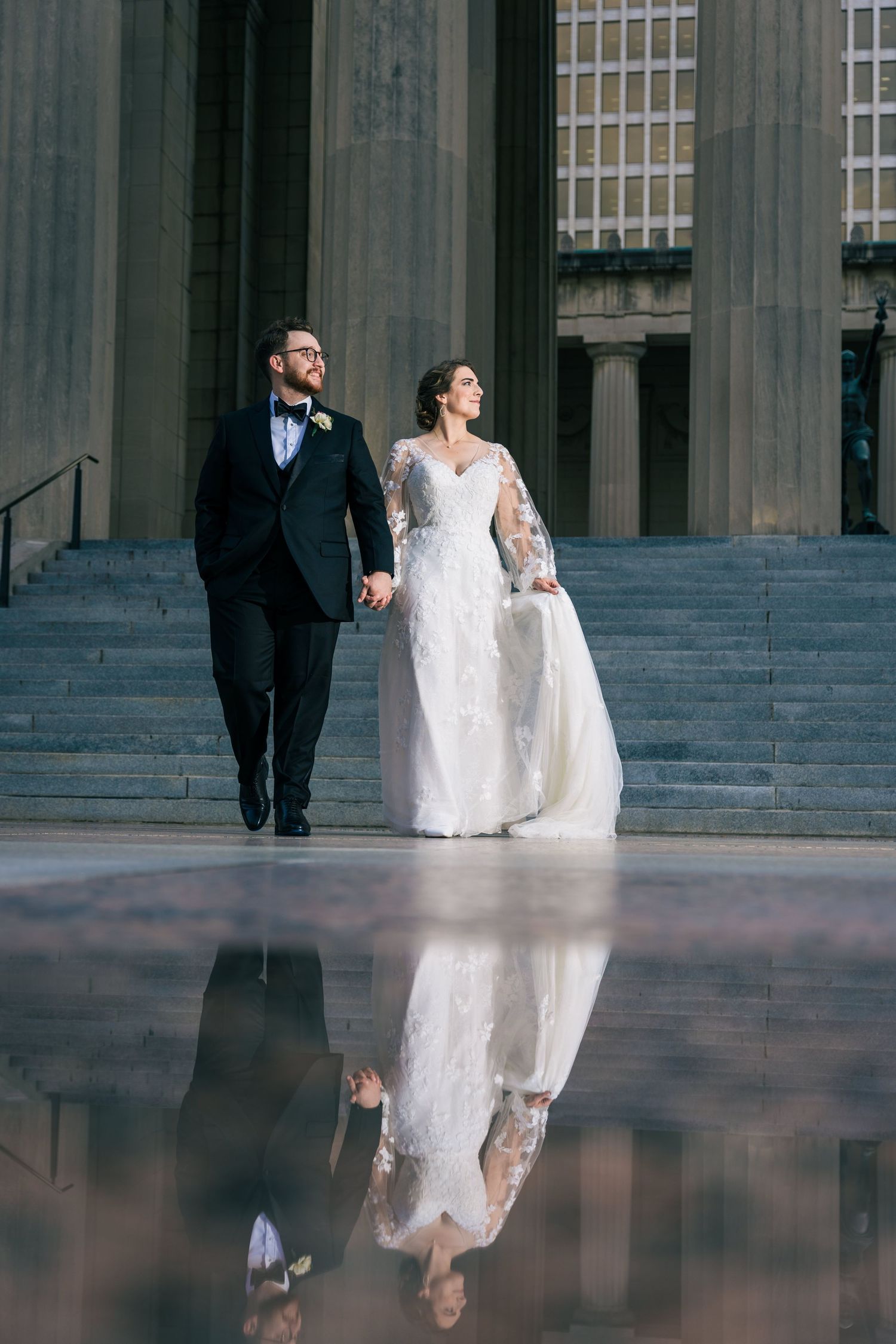 Wedding couple walks together on steps with beautiful reflection in foreground. War Memorial Plaza., Nashville, Tennessee