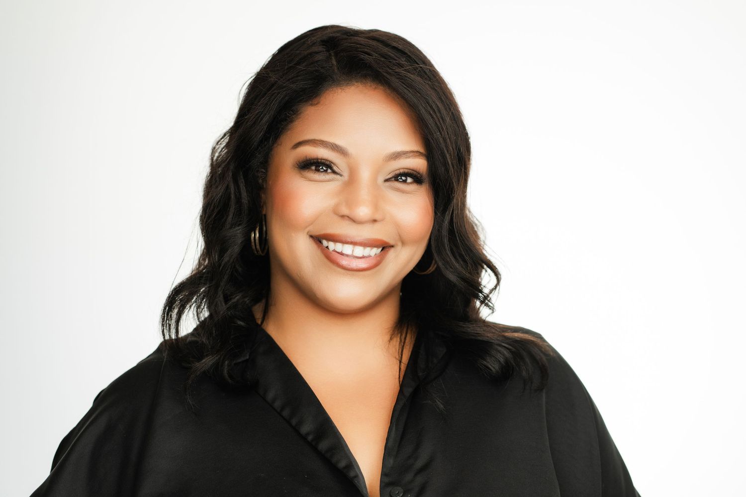 Professional headshot of woman in black blouse smiling against white background. Nashville, Tennessee.
