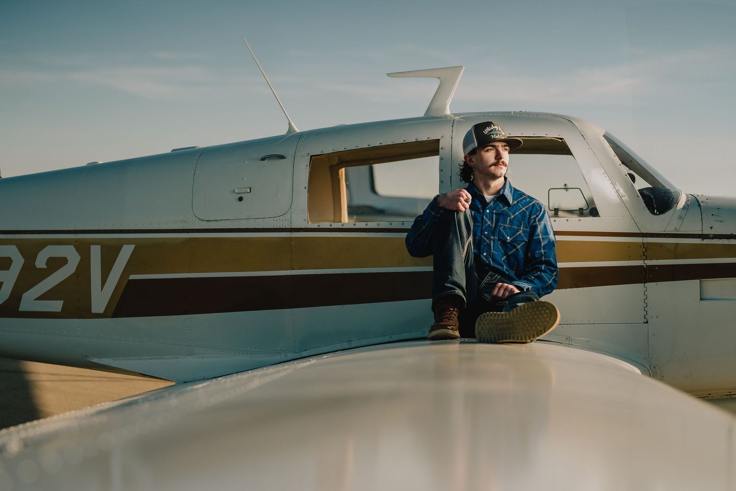 Aviation themed portrait of pilot sitting on wing of small private aircraft. Nashville, Tennessee.