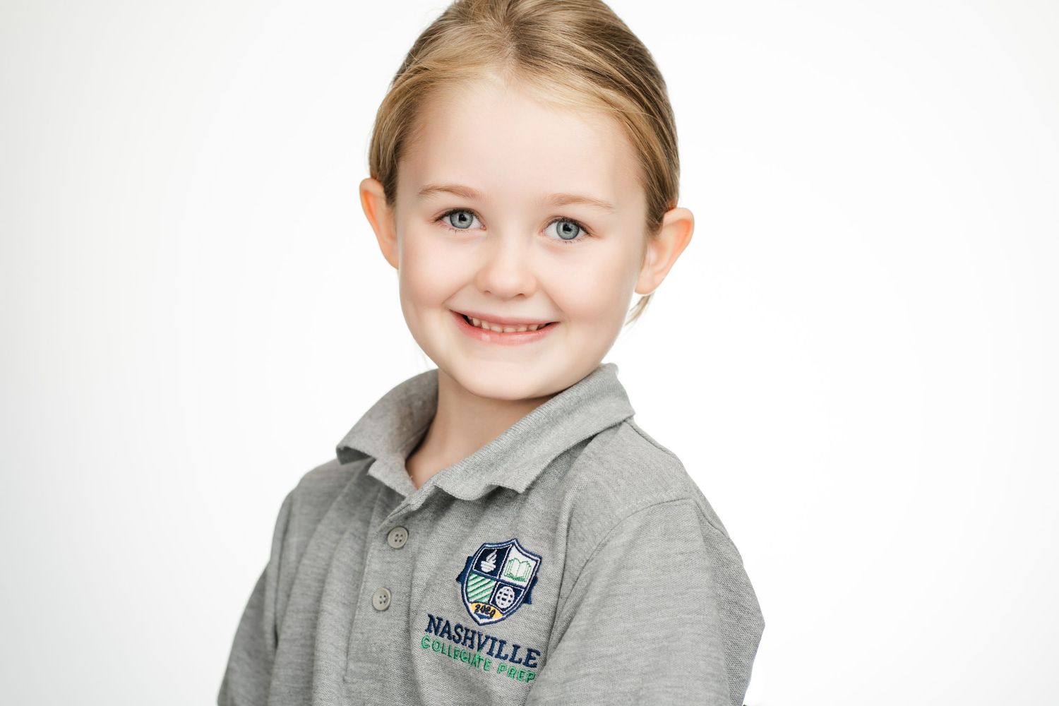 Professional portrait of a young student in a gray school uniform polo against a white background. Nashville, Tennessee.