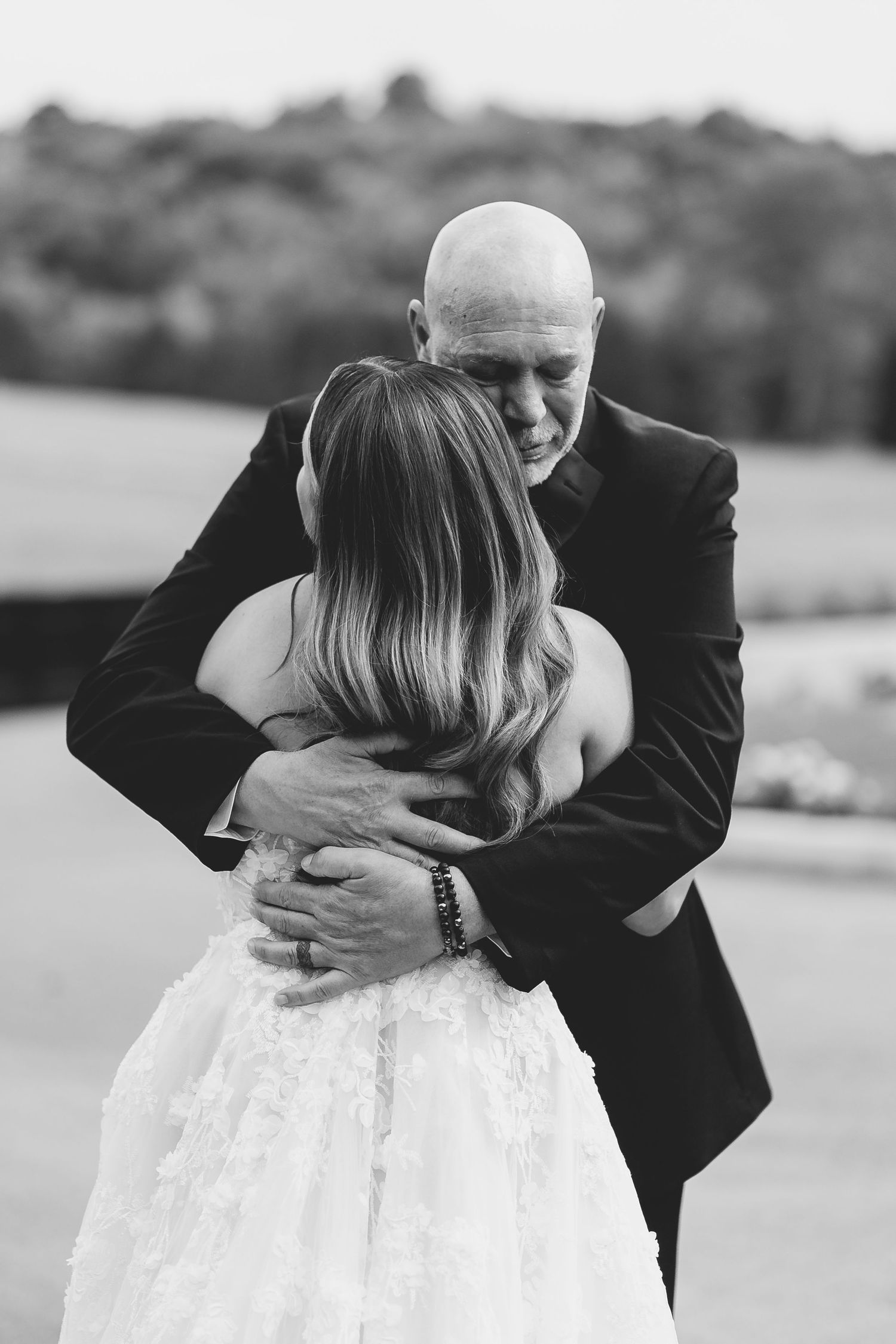 A touching black and white moment between a bride in a white dress and her dad in a suit embracing. Nashville, Tennessee.