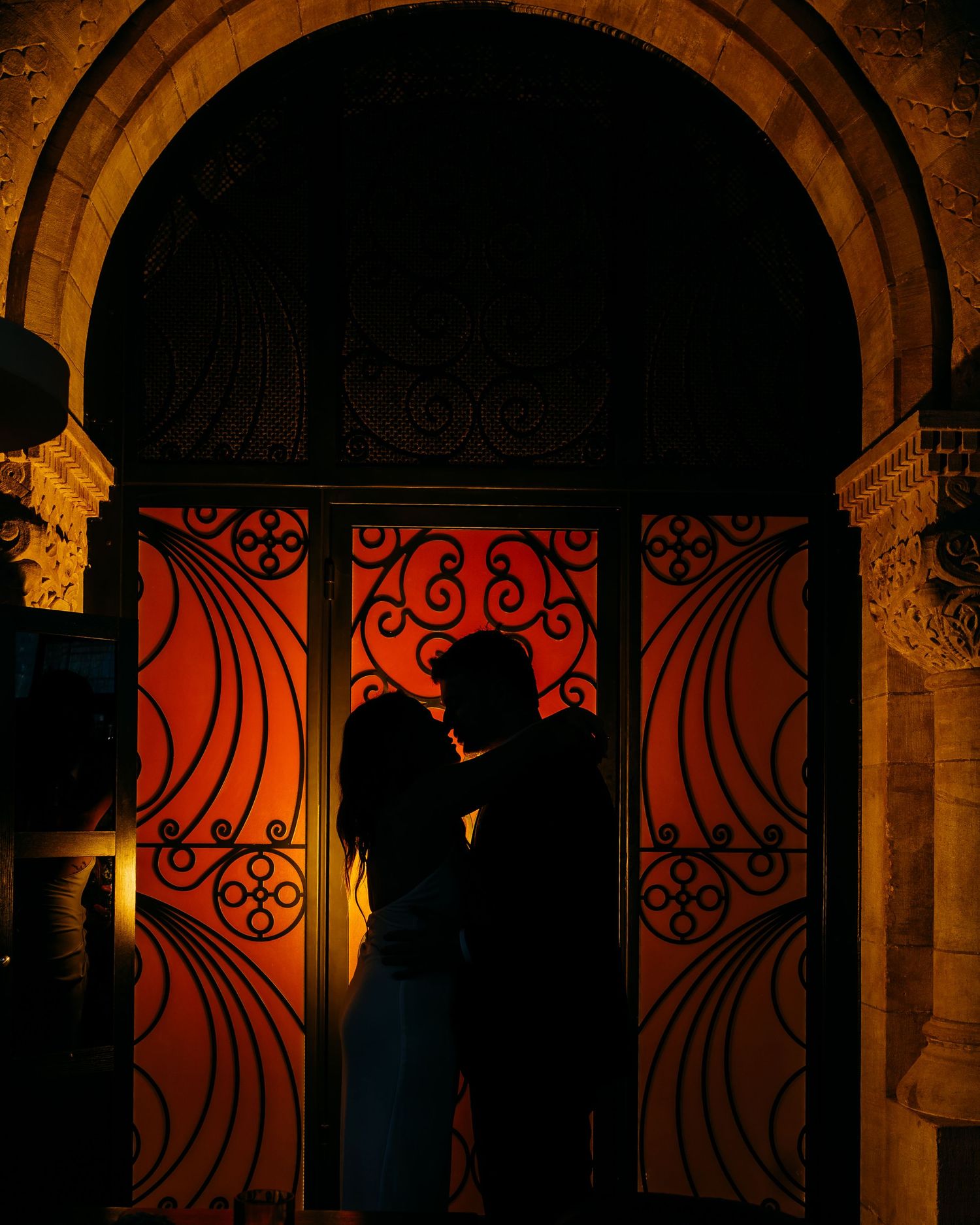 Dramatic silhouette of couple embracing in ornate archway with red backlight. Nashville, Tennessee.