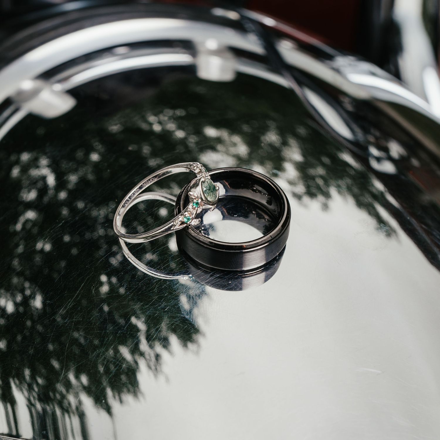 Wedding rings resting on a reflective surface with tree shadow patterns. Indiana.