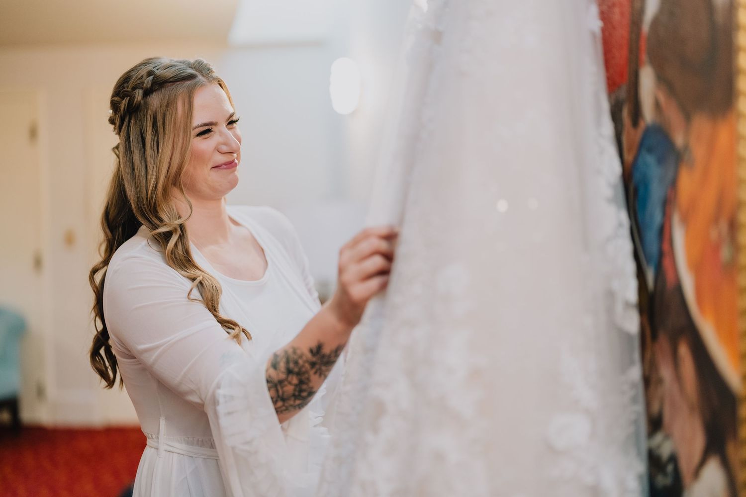 A person wearing a white robe examines a wedding dress during pre-ceremony preparations. Milwaukee, Wisconsin.