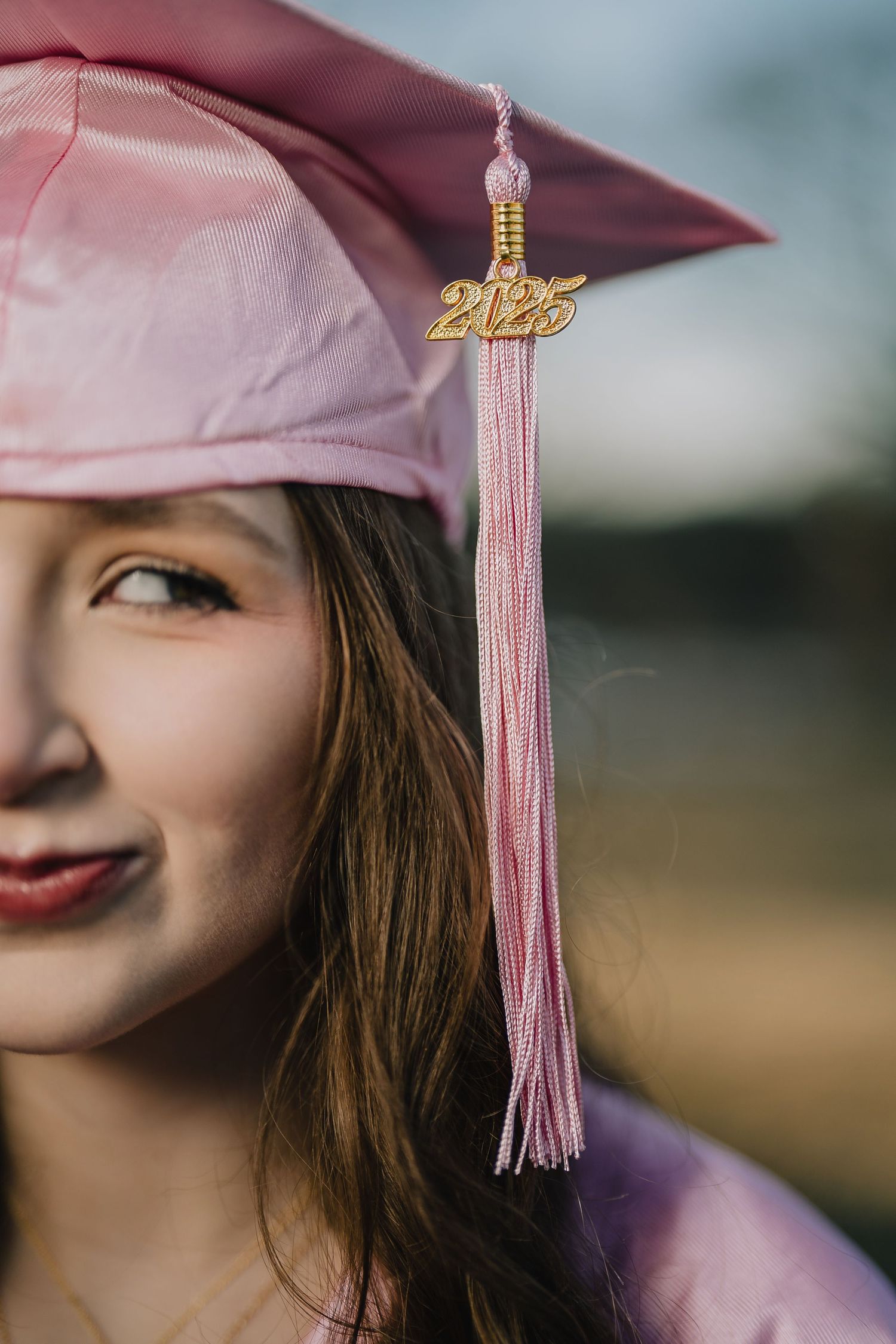 Close-up graduation photo showing pink cap and tassel with 2023 charm against blurred background. Nashville, Tennessee.