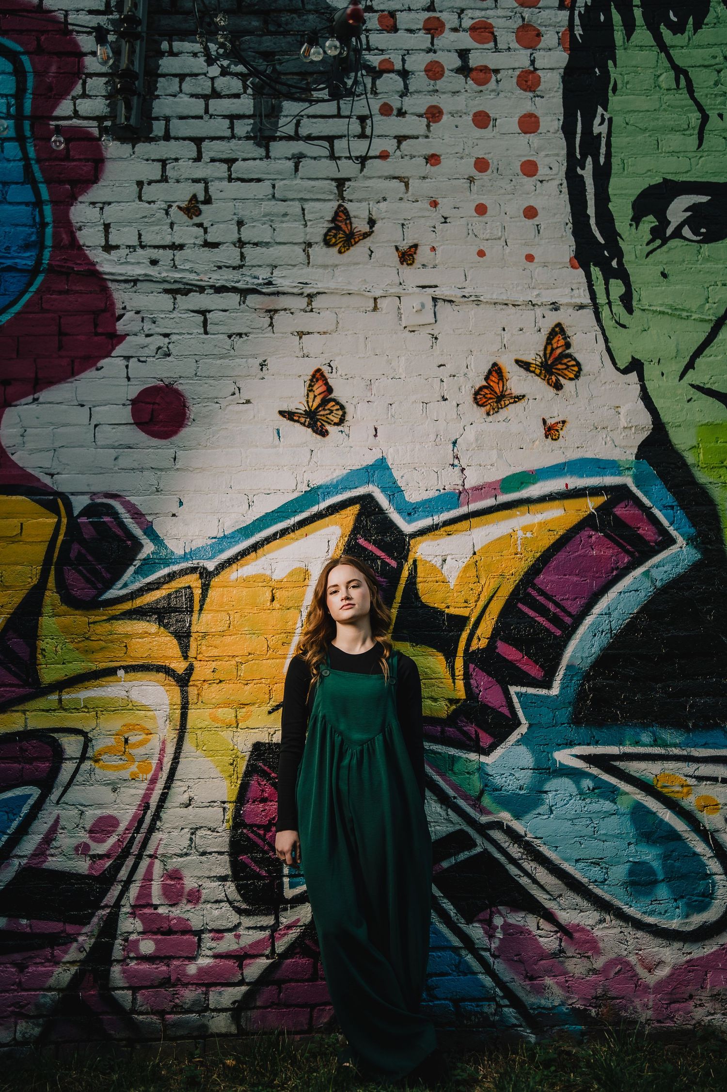 Artistic portrait against graffiti wall with painted butterflies and street art. Nashville, Tennessee.